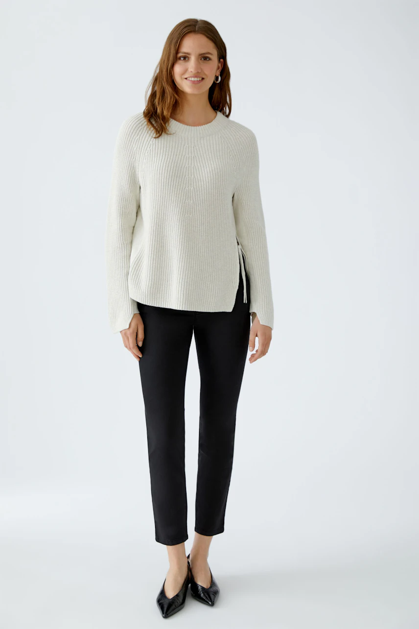 Damen-Pullover: Frau in hellem, strukturiertem Pullover mit lässigem Schnitt und schwarzen Leggings.