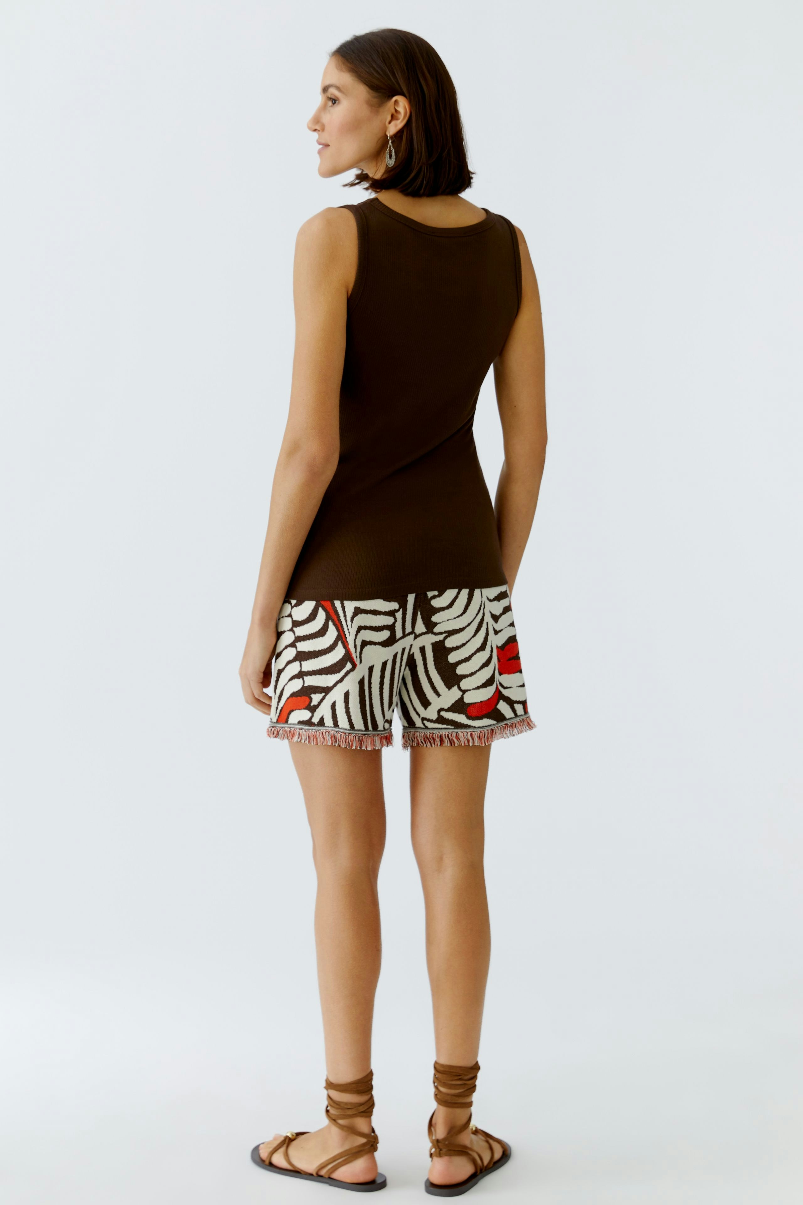 Casual women's top: A woman in a brown sleeveless top paired with a patterned skirt, showcasing a relaxed style.
