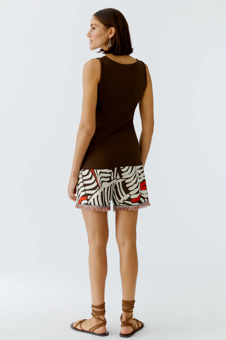 Casual women's top: A woman in a brown sleeveless top paired with a patterned skirt, showcasing a relaxed style.