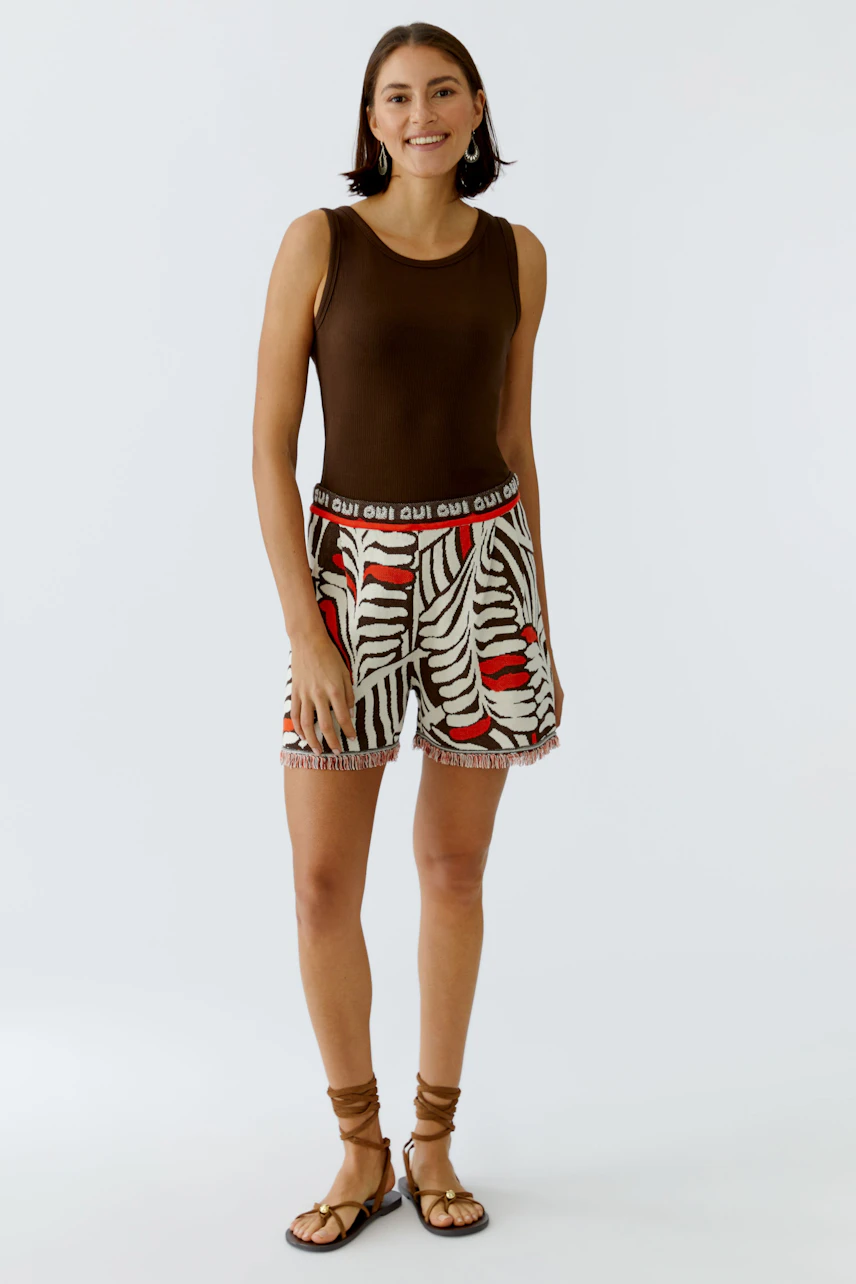 Casual women's top: A woman in a brown tank top paired with patterned shorts, showcasing a relaxed summer look.