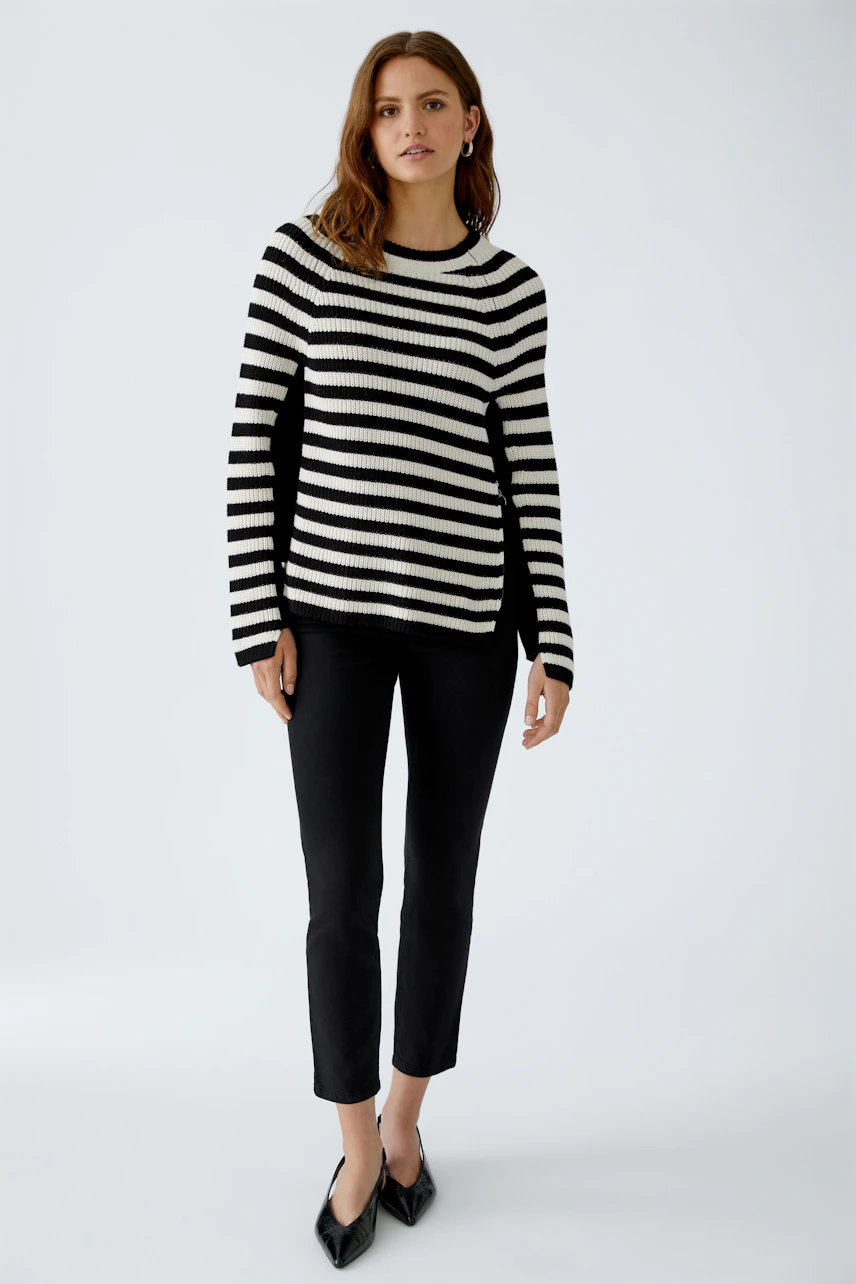 Stylish women's pullover: A woman in a black and white striped pullover paired with black pants.