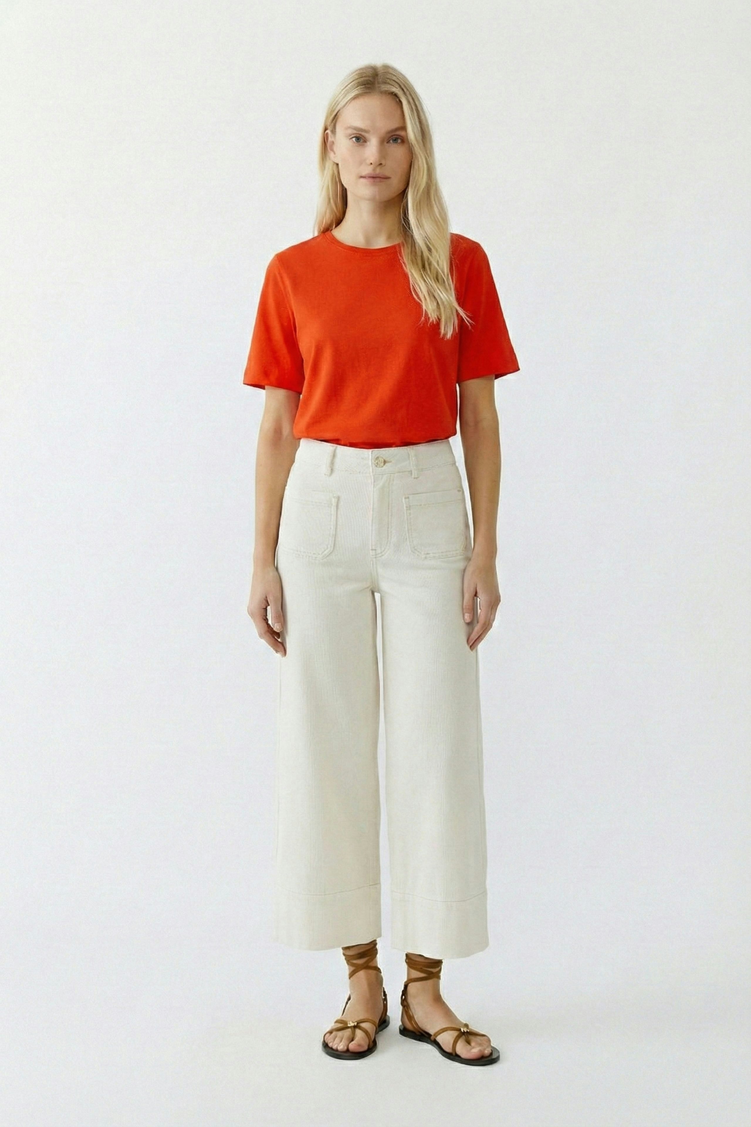 Casual women's T-shirt: Young woman in a bright red tee paired with light wide-leg pants.