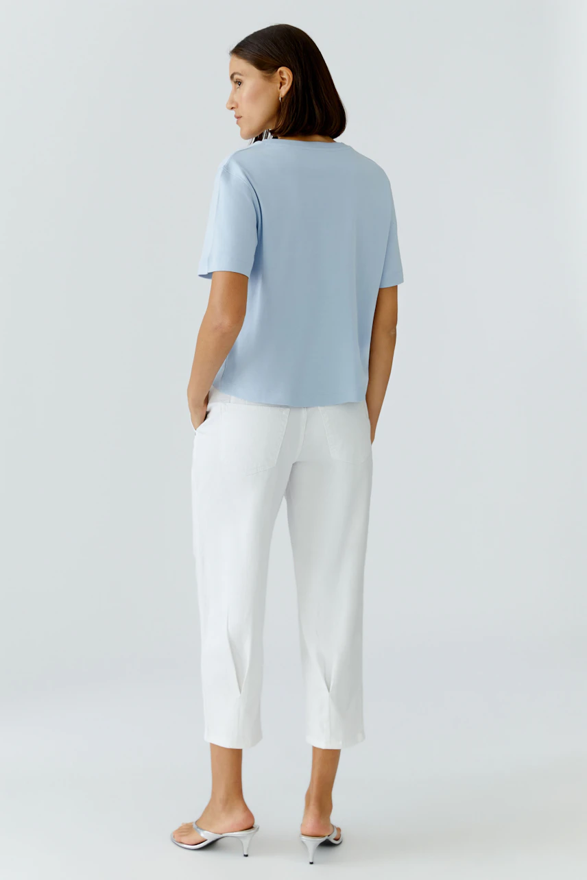 Damen-T-Shirt: Frau in hellblauem T-Shirt und weißen Hosen, lässig und modern.