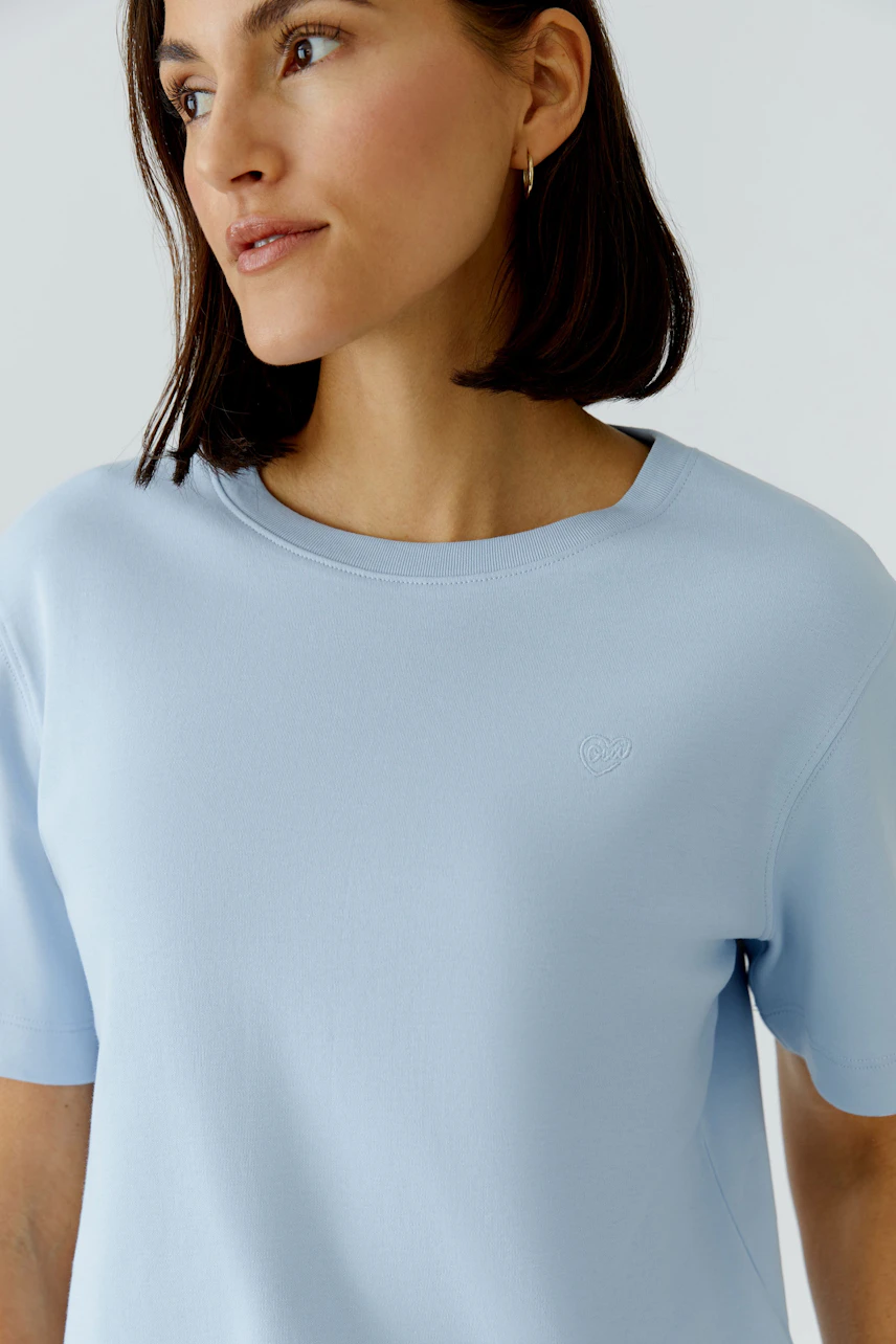Bequemes Damen-T-Shirt: Frau in hellblauem T-Shirt mit Rundhalsausschnitt und kurzen Ärmeln.