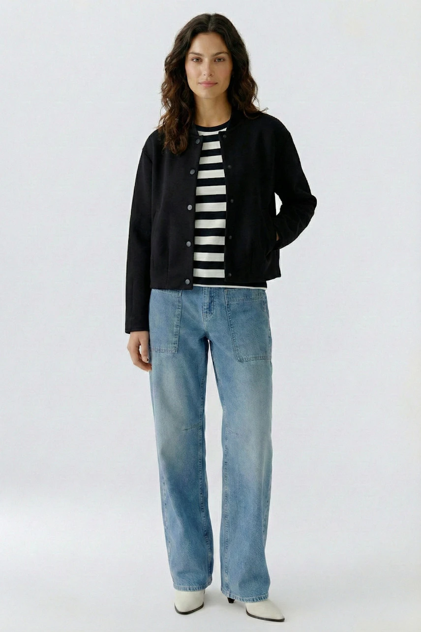Lässiger Damen-Blouson: Frau im schwarzen Blouson über gestreiftem Shirt und Jeans, entspanntes Auftreten.