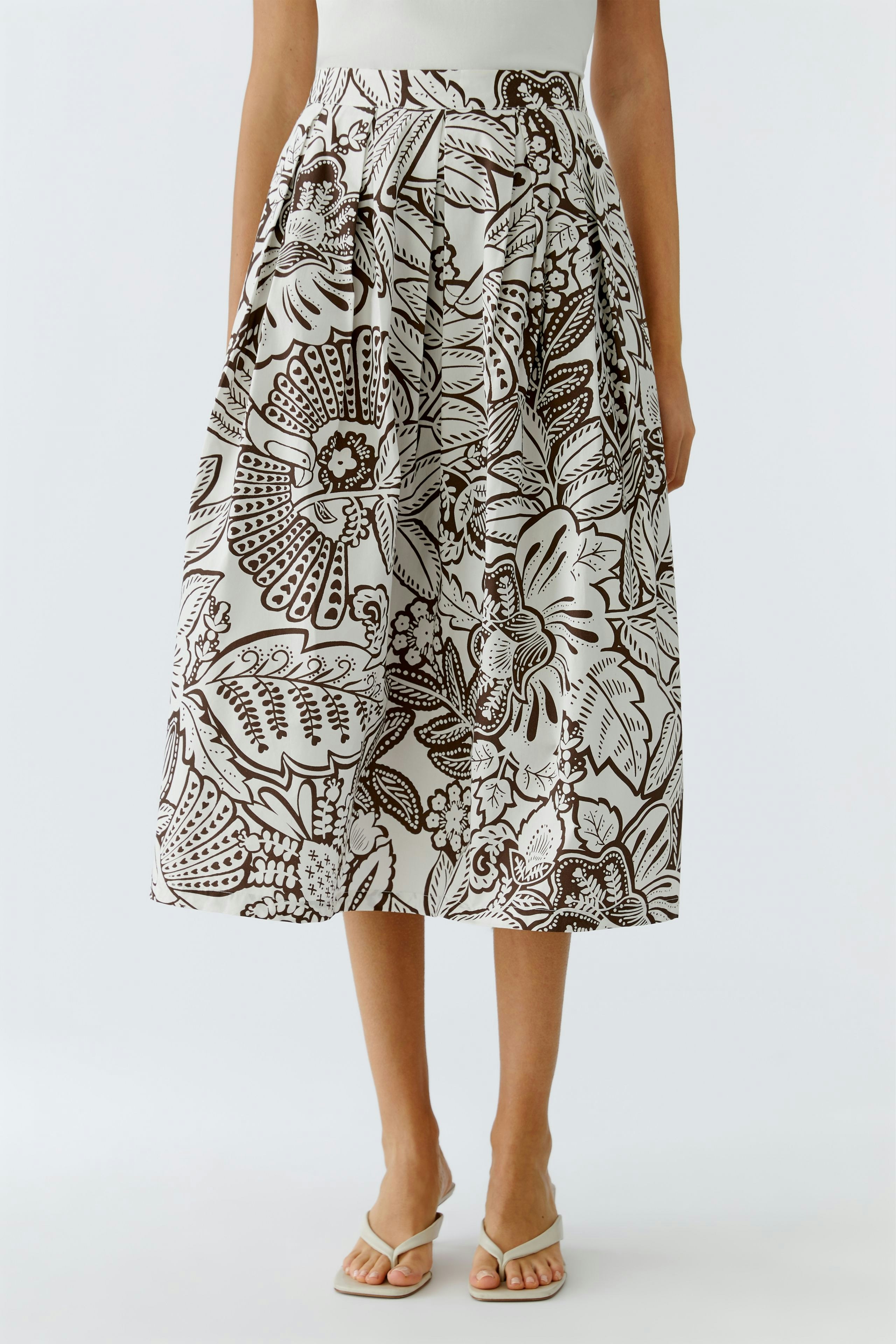 Faltenrock: Frau trägt einen gemusterten Rock mit weitem Schnitt und lässigem Design.