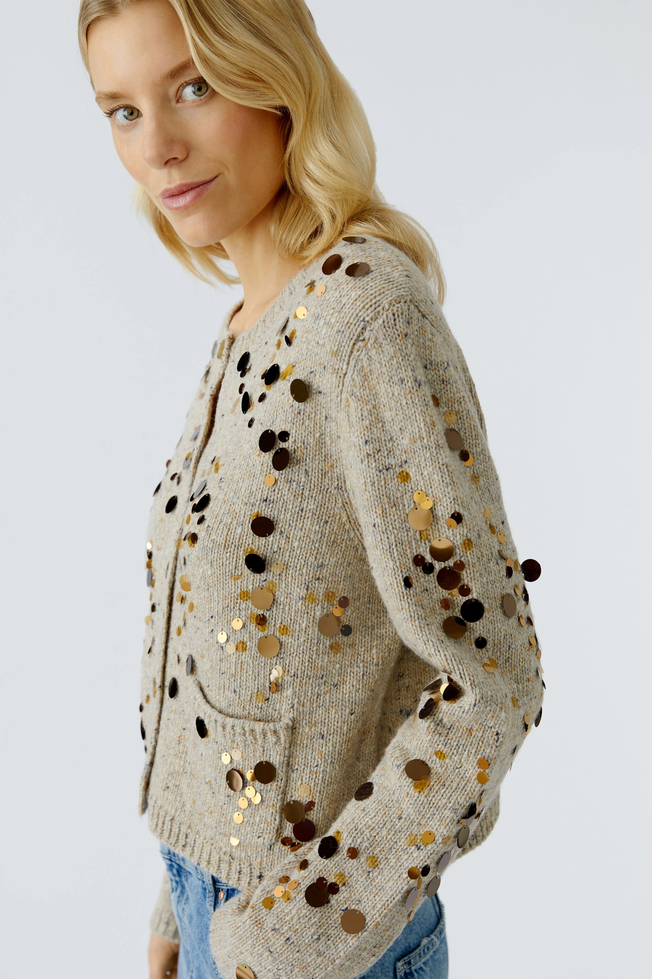 Beige Strickjacke mit Pailletten: Frau trägt eine lässige Strickjacke mit glitzernden Details.