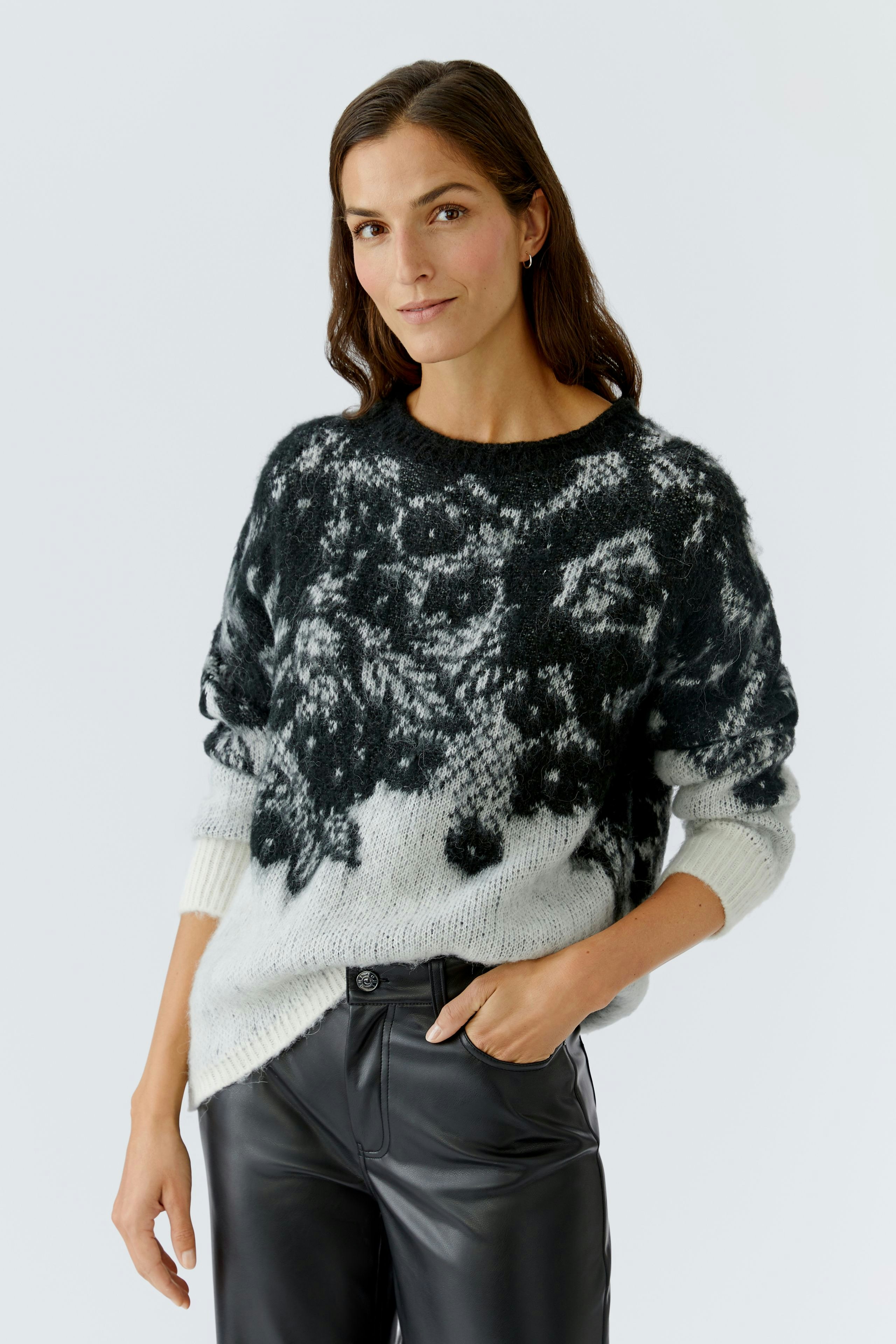 Damen-Pullover: Frau in einem schwarz-weißen, gemusterten Strickpullover mit lässigem Schnitt.