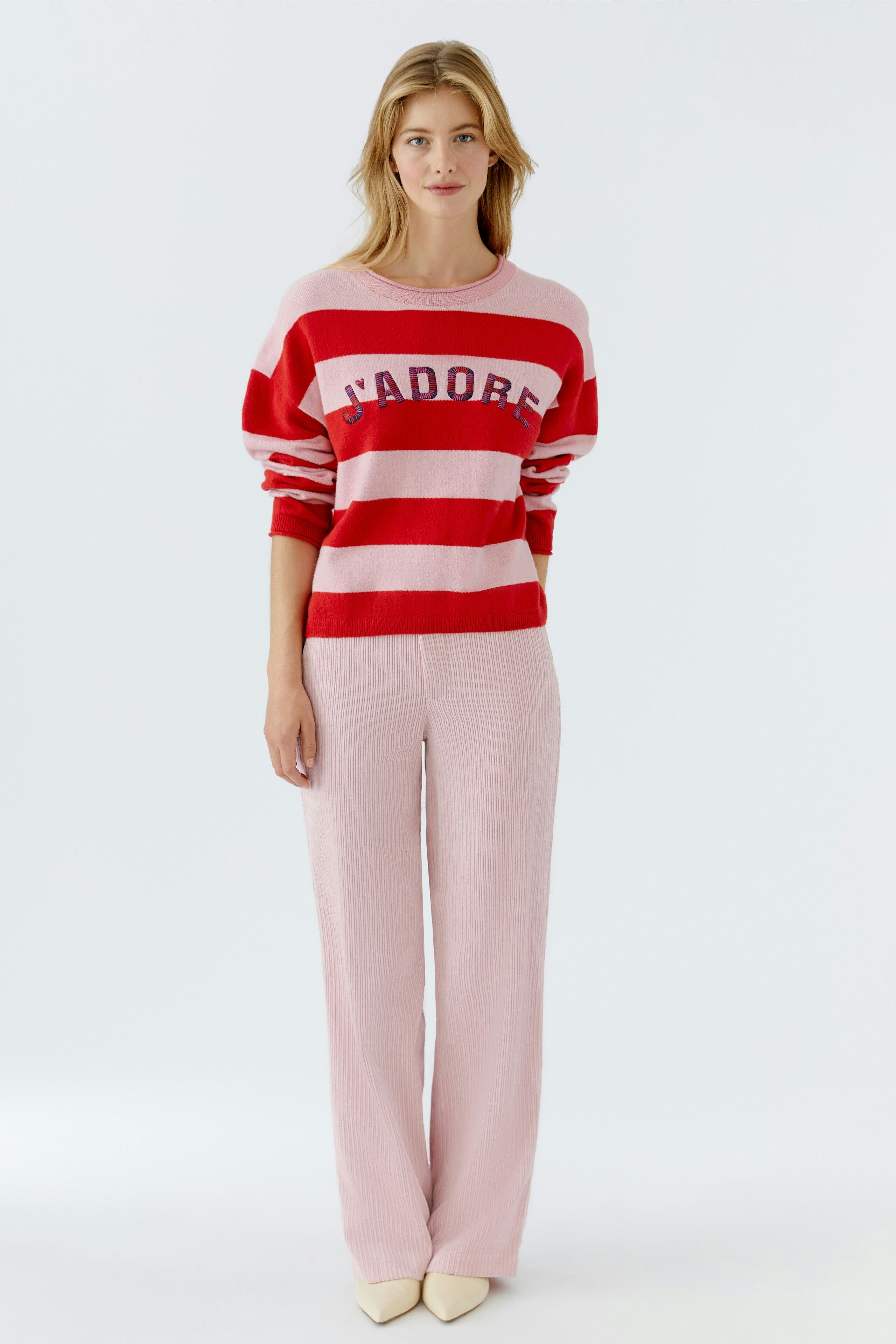 Casual women's pullover: Young woman in a red and pink striped pullover with 'J'adore' lettering.
