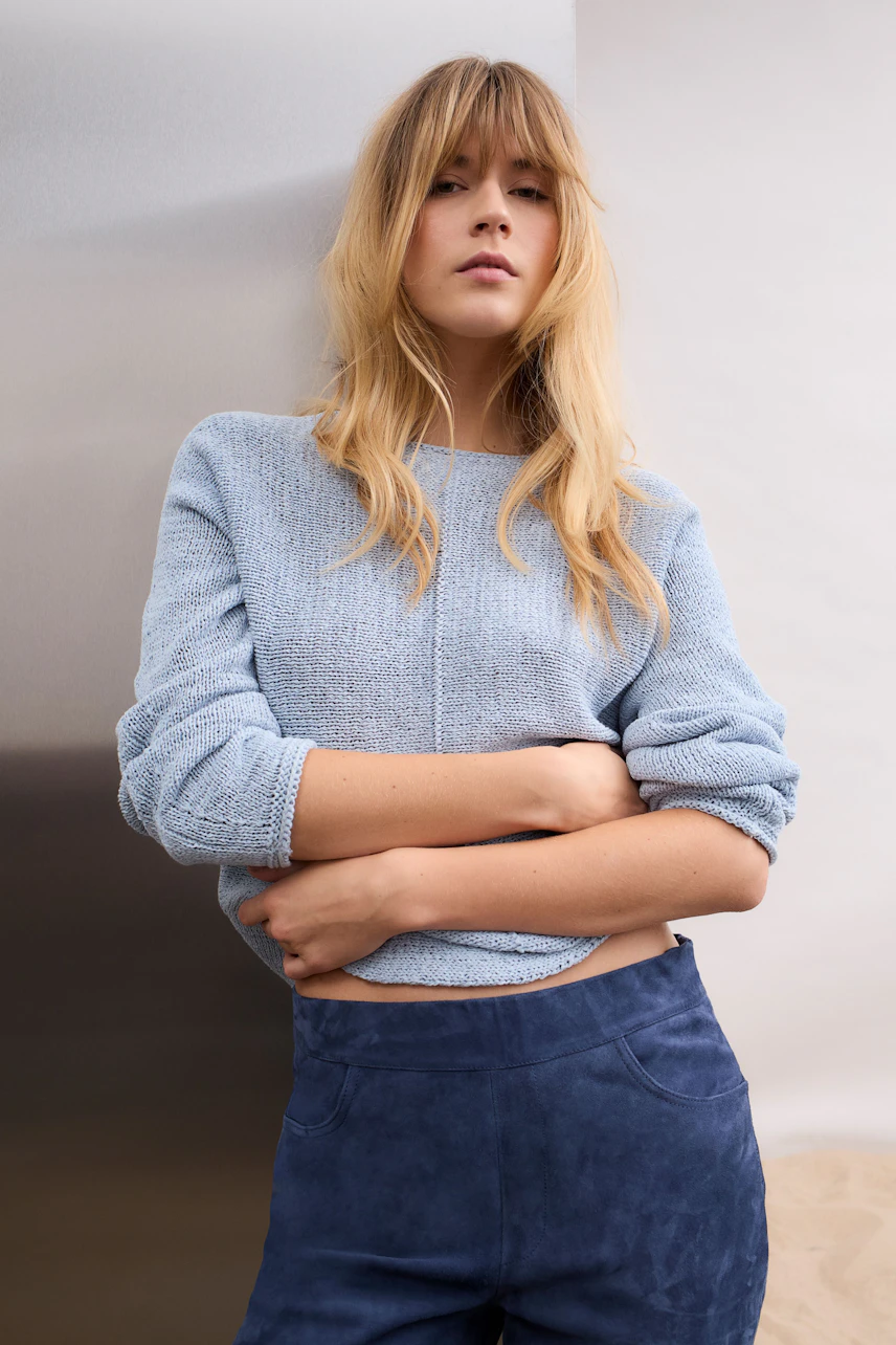 Casual women's pullover: Woman in light blue knit pullover with relaxed fit, arms crossed, confident look.