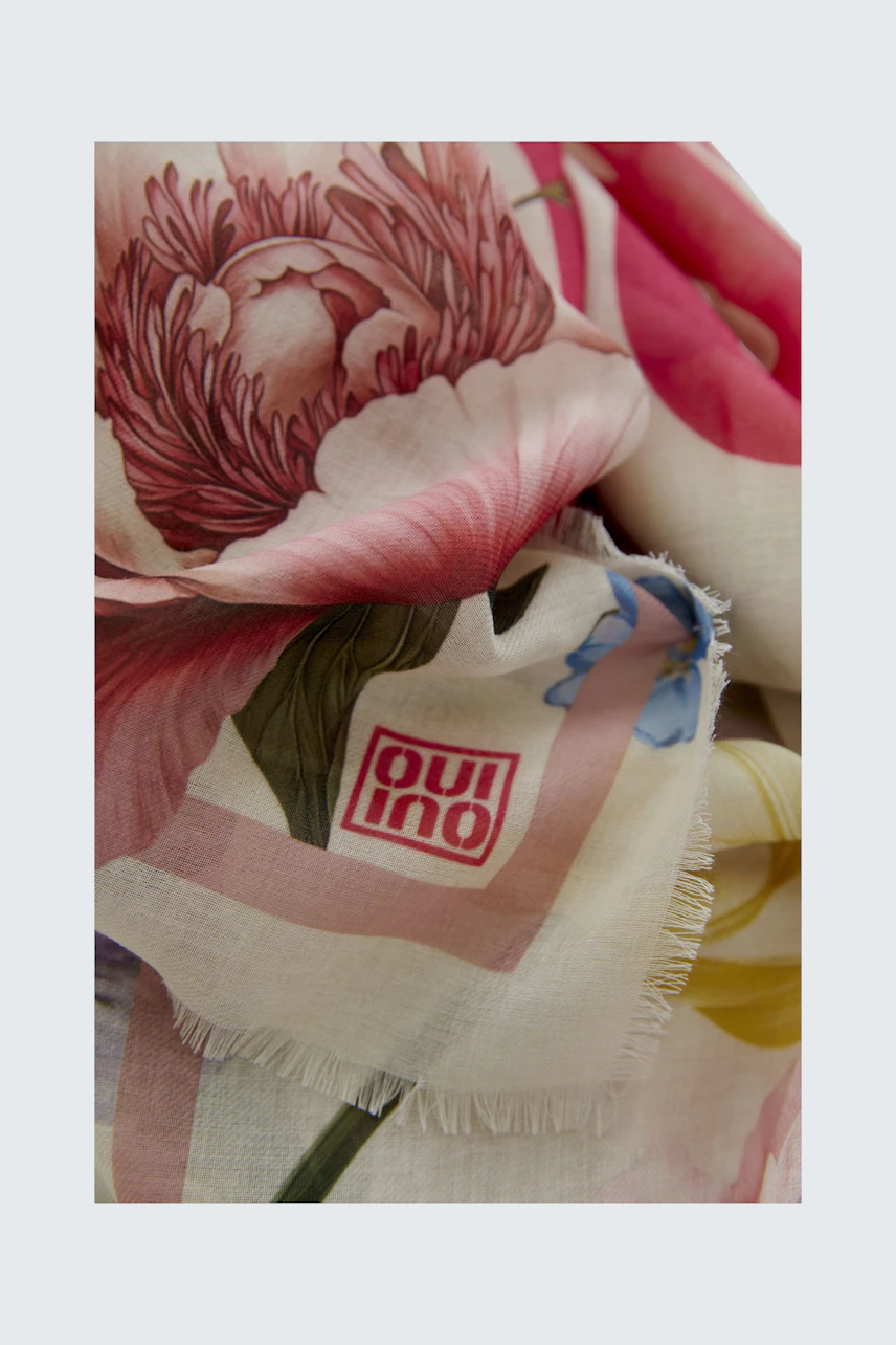 Floral scarf with vibrant pink and yellow blooms, soft fabric, and fringed edges.
