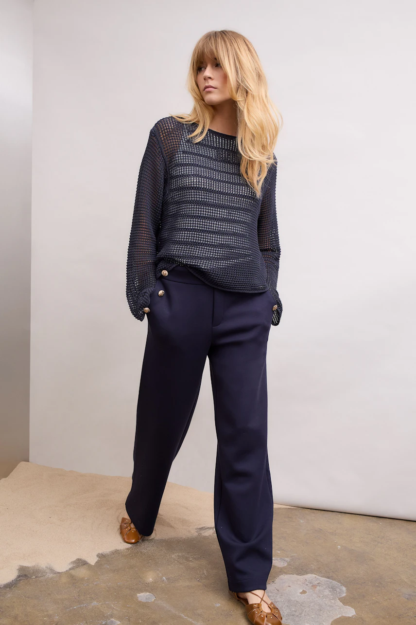 Casual tank top: Woman in a navy mesh top and wide-leg pants, standing confidently.