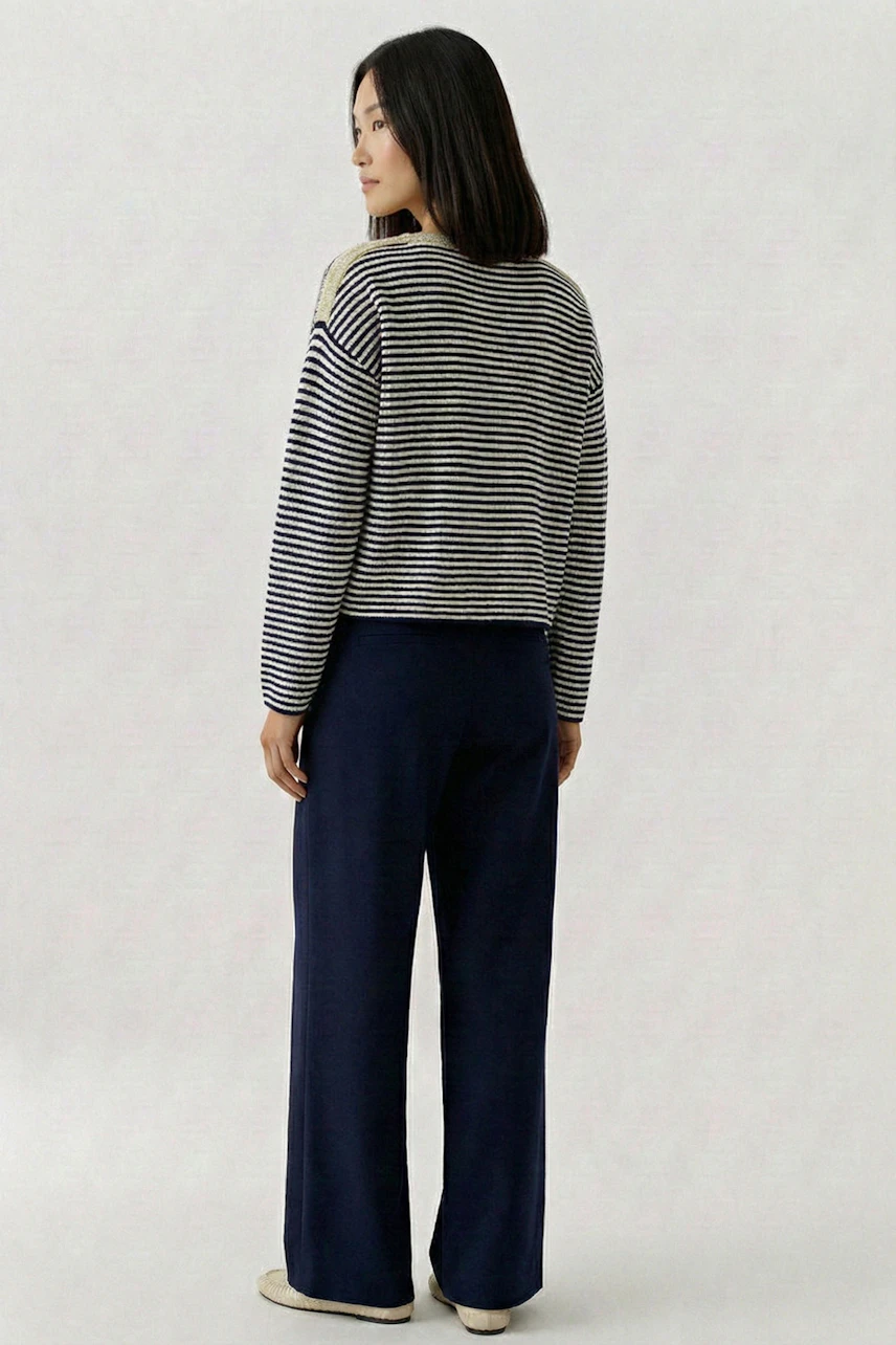 Casual women's pullover: Woman in striped pullover and navy pants, looking to the side.