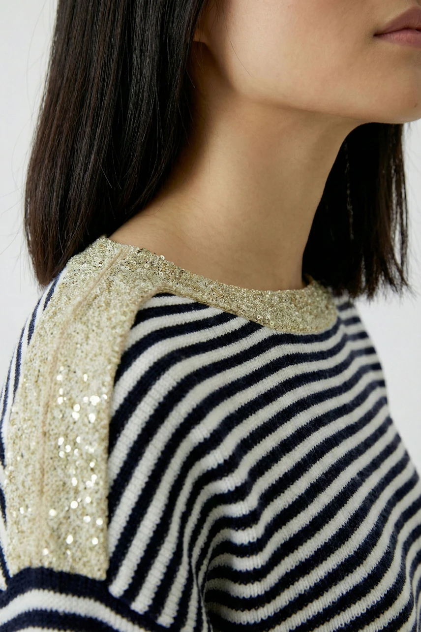 Striped pullover: Woman in a navy and white striped pullover with gold sequin details on shoulders.