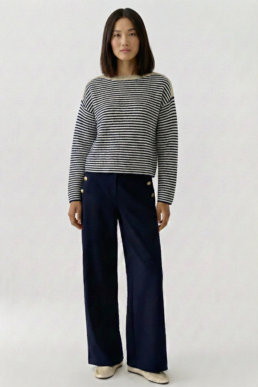 Casual women's pullover: Woman in striped pullover and navy pants stands confidently.