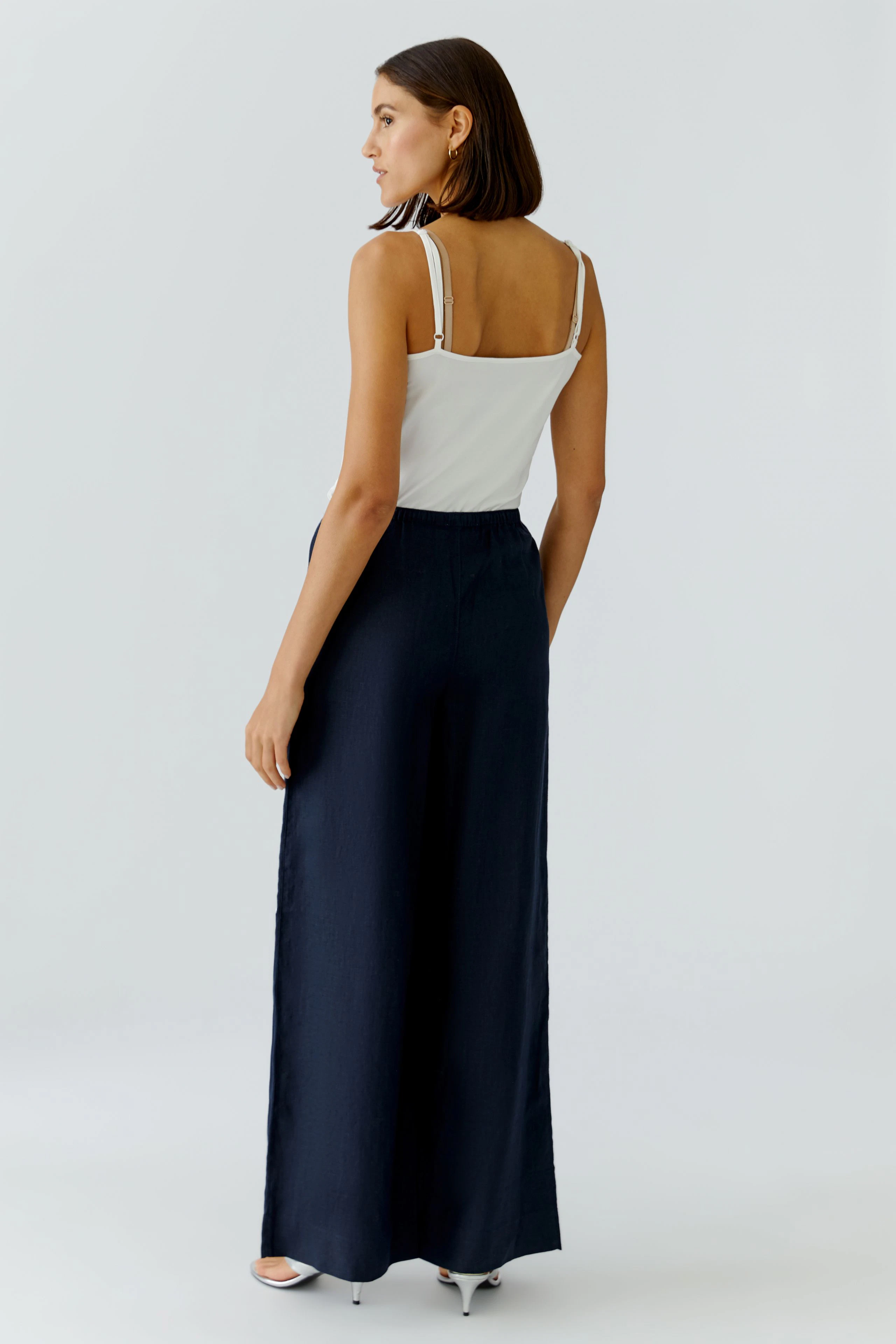 Damen-Marlenehose: Frau in navyfarbener Hose mit weitem Bein und elastischem Bund von hinten.