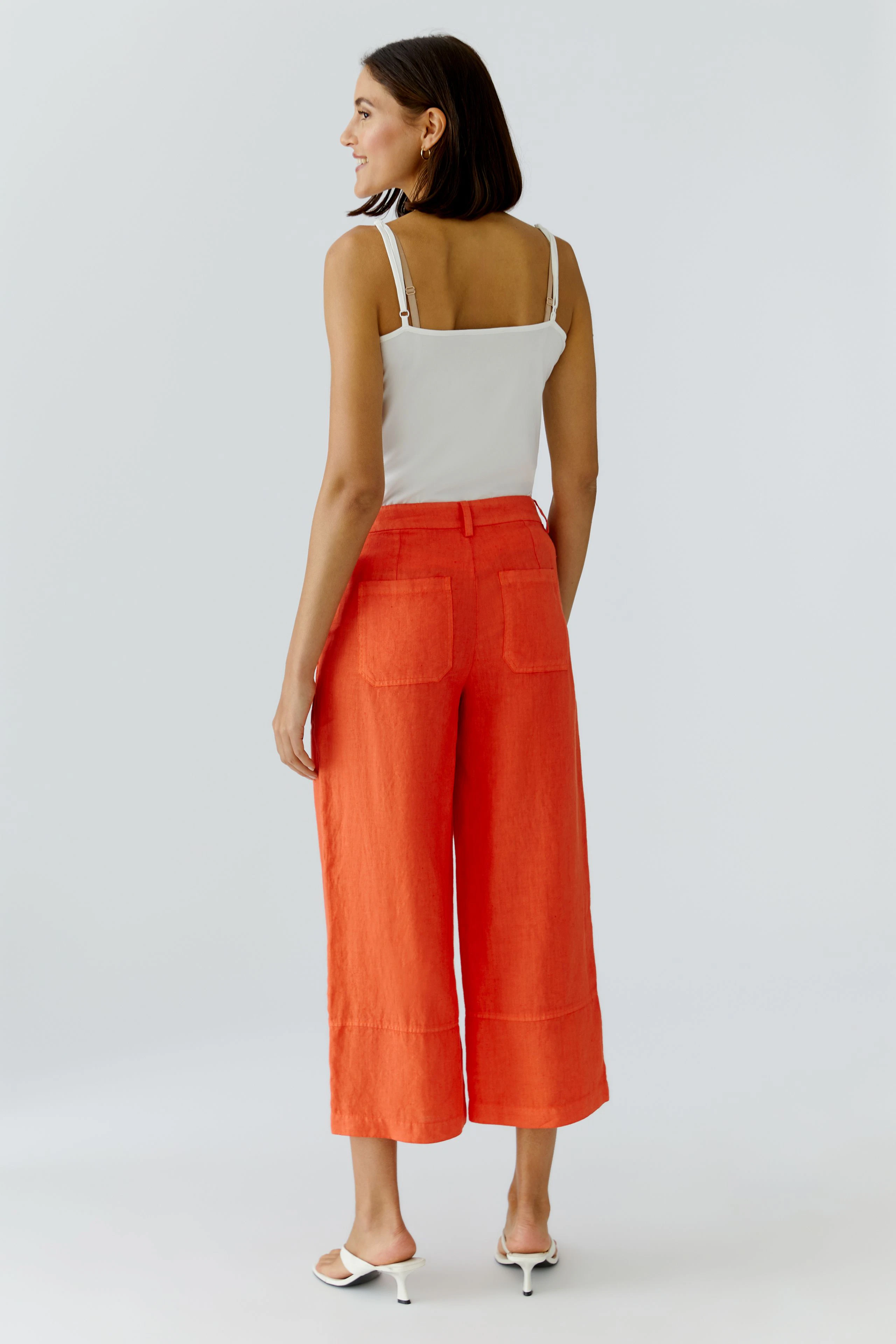 Bequeme Damen-Hose: Frau trägt eine lässige, orangefarbene Hose mit weitem Bein und praktischen Taschen.