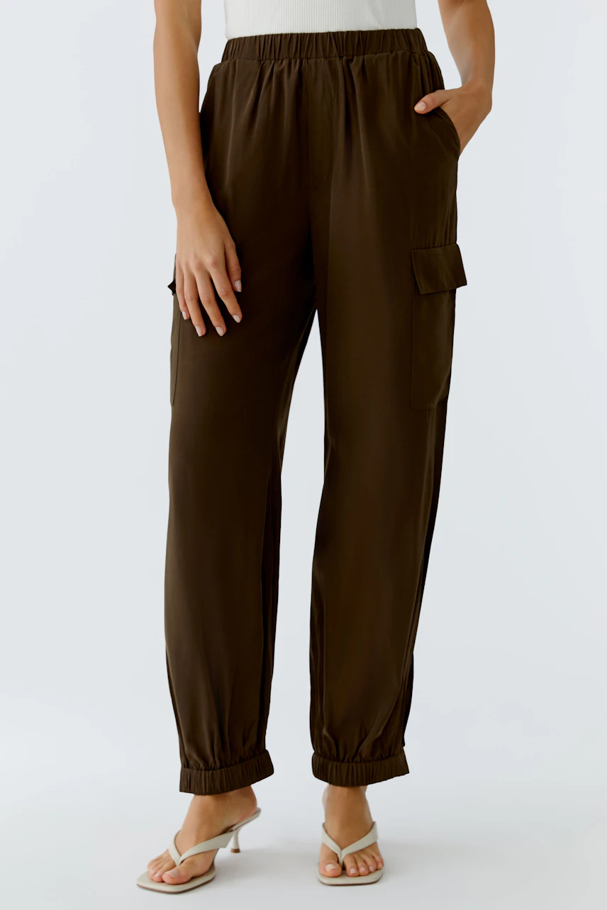 Casual women's cargo pants: A woman in brown cargo pants with elastic cuffs and pockets stands confidently.