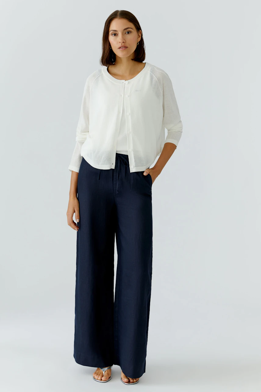 Casual women's cardigan: A woman in a light white cardigan paired with navy wide-leg pants.