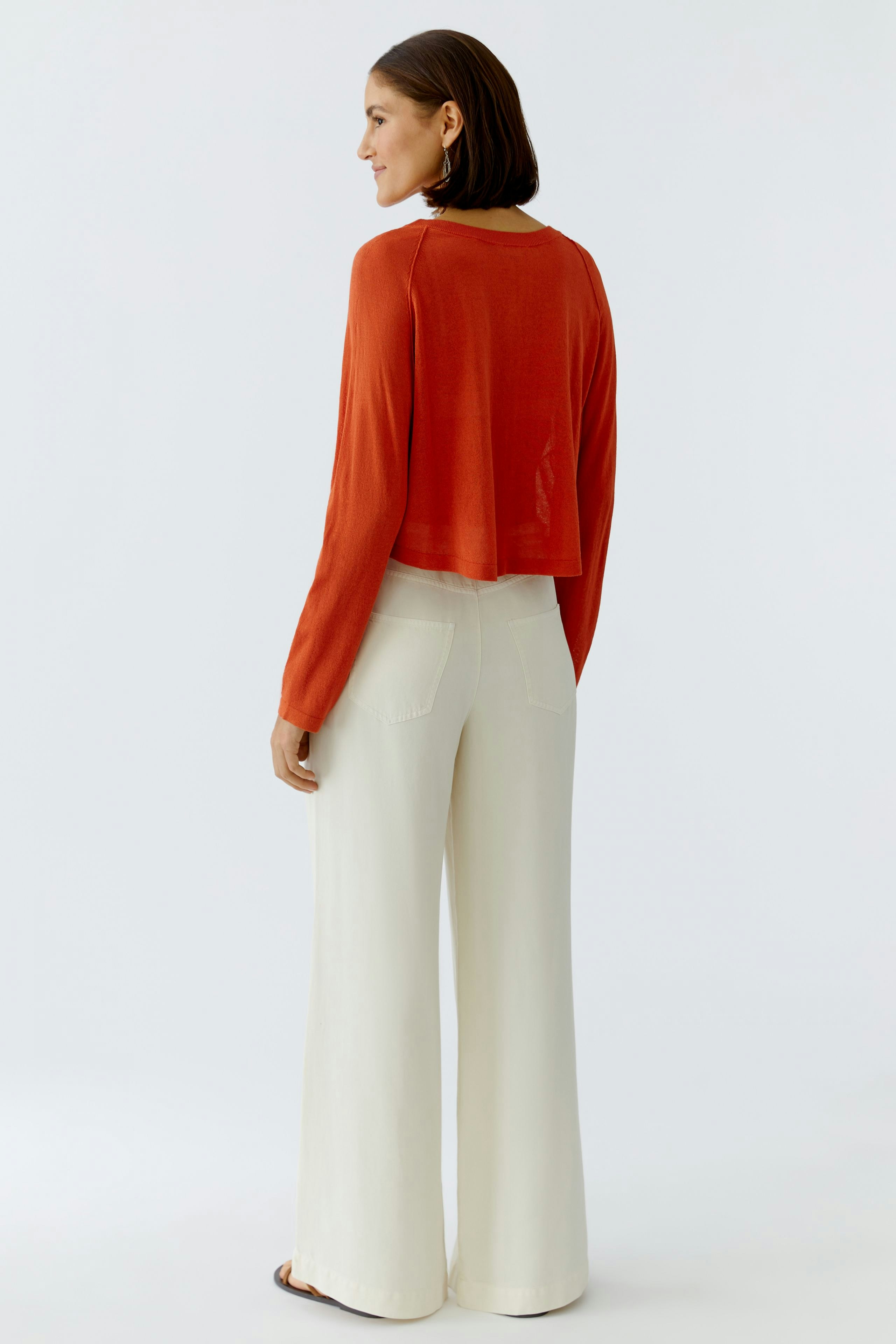 Damen-Strickjacke: Frau in roter, lässiger Strickjacke mit langen Ärmeln und lockerer Passform.