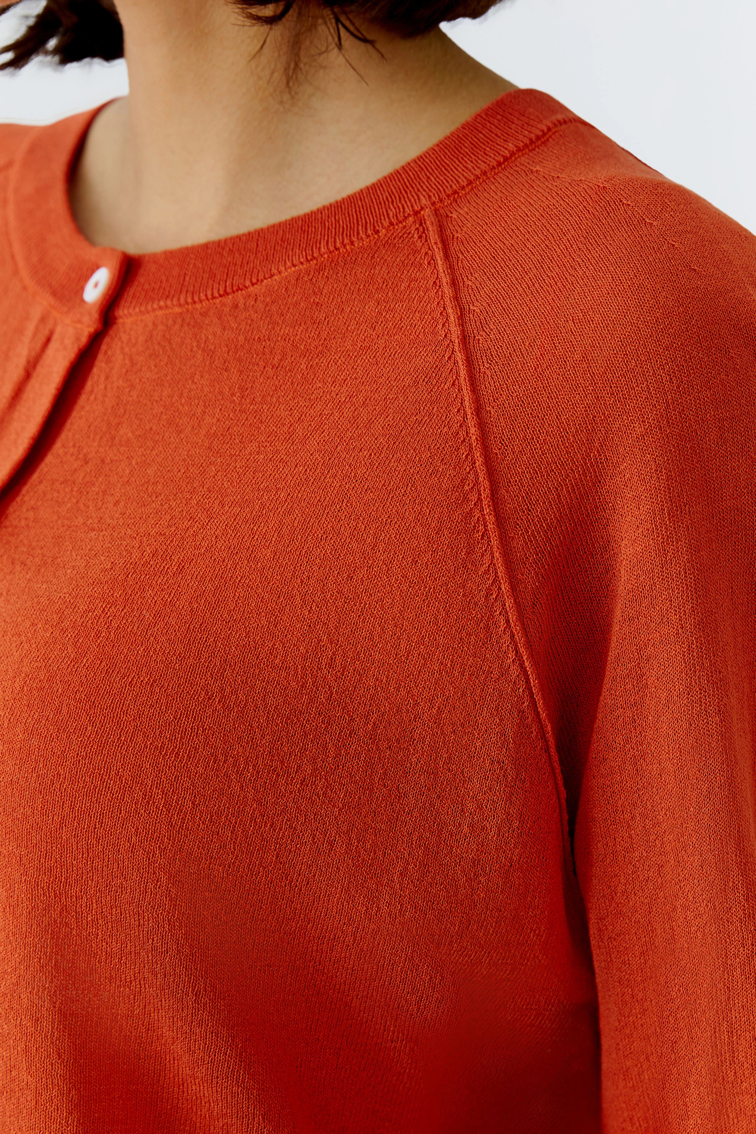 Bequeme Damen-Strickjacke in leuchtendem Orange mit Rundhalsausschnitt und Knopfdetails.