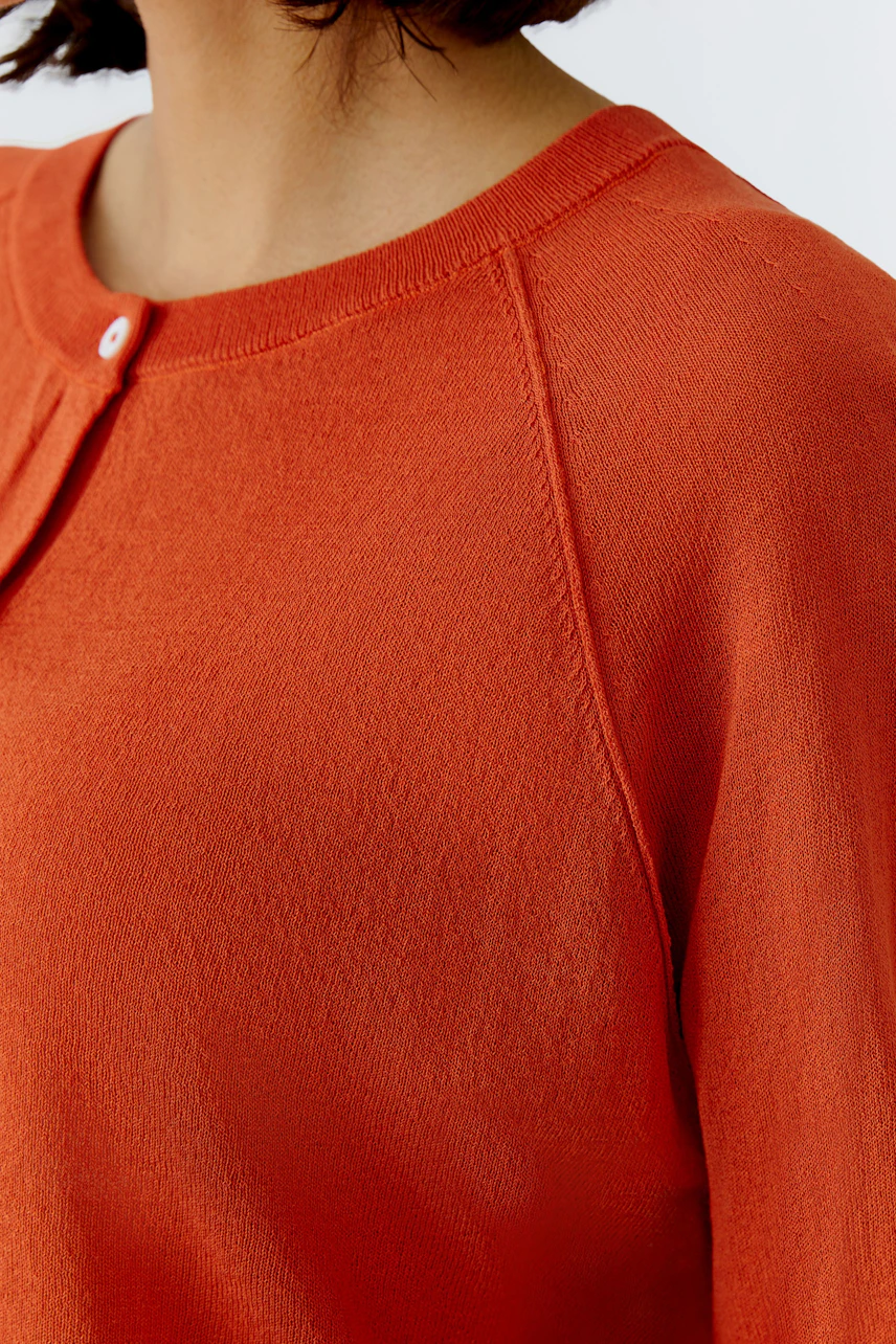 Bequeme Damen-Strickjacke in leuchtendem Orange mit Rundhalsausschnitt und Knopfdetails.