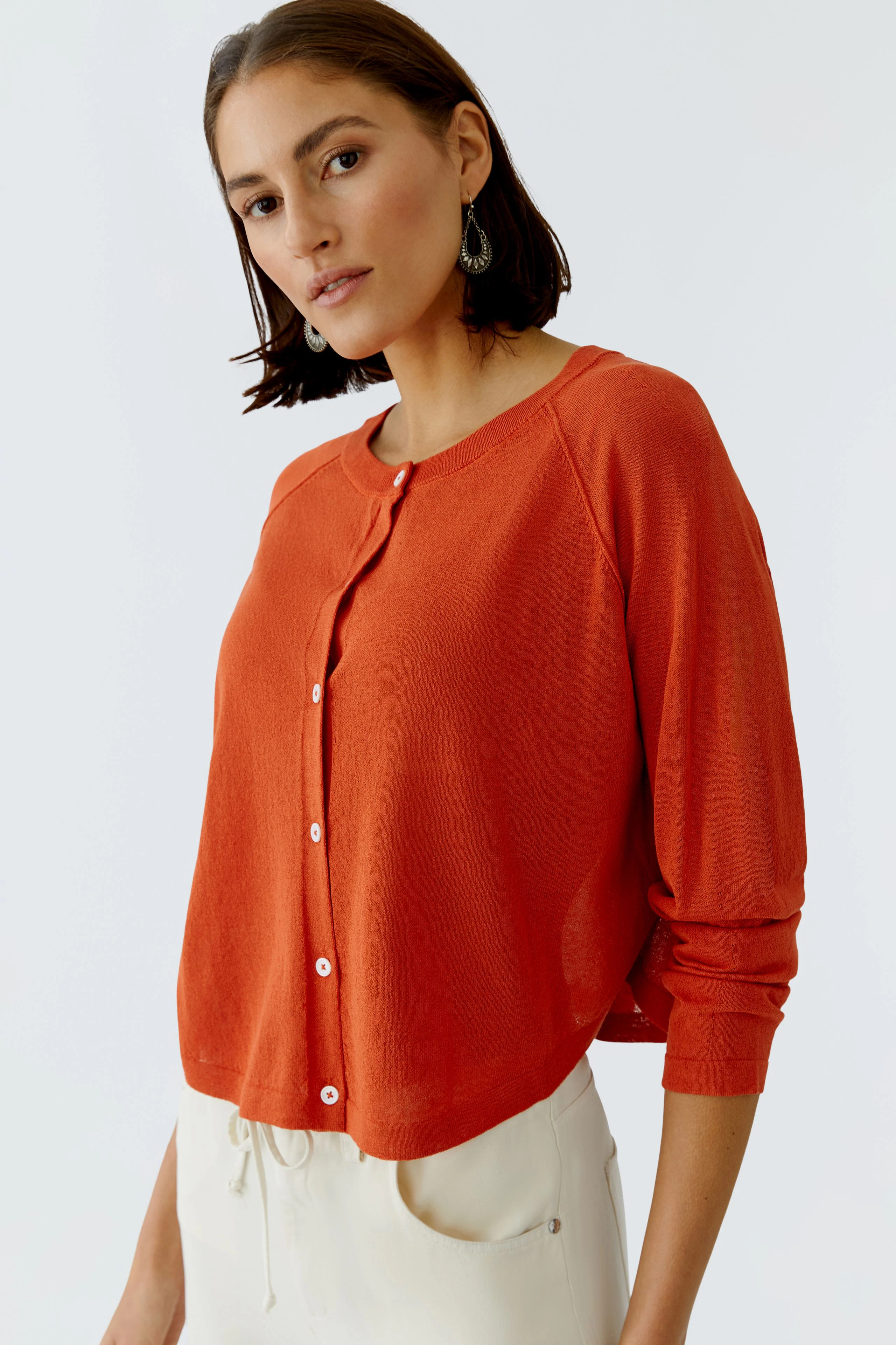 Damen-Strickjacke: Frau in roter Strickjacke mit Knöpfen und lässigem Schnitt, ideal für den Alltag.