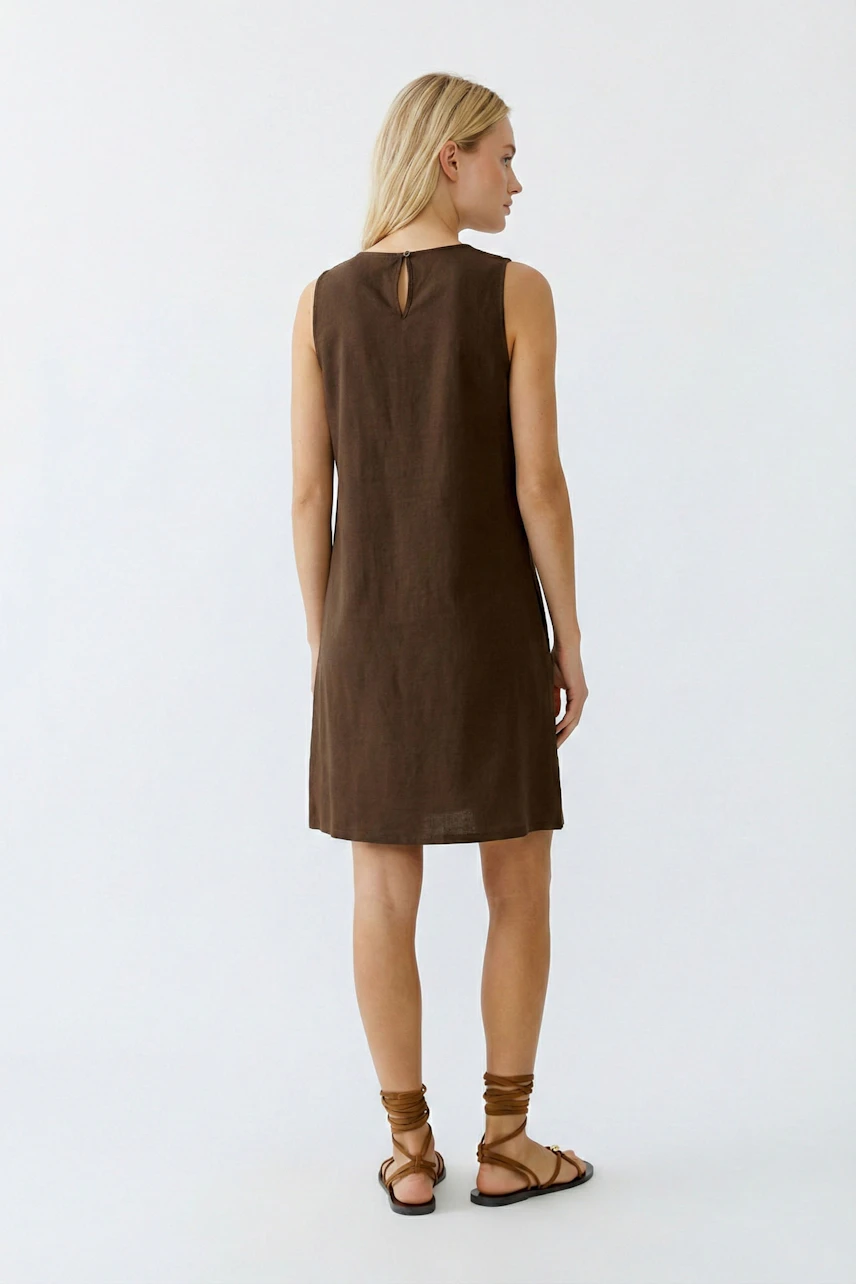 Casual A-line dress: Woman in a brown sleeveless dress with a keyhole back, paired with strappy sandals.