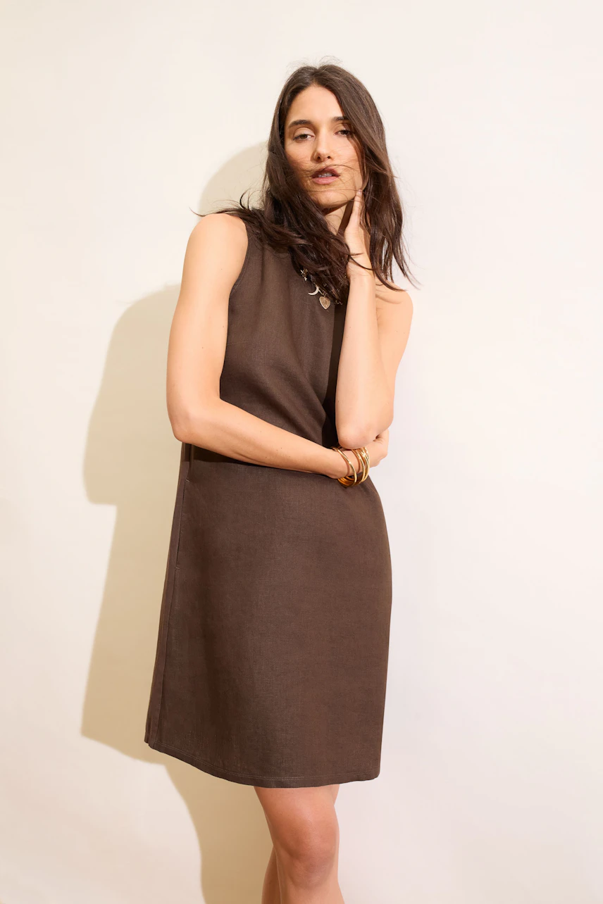 Casual A-line dress: Woman in sleeveless brown dress, relaxed pose, minimal accessories.