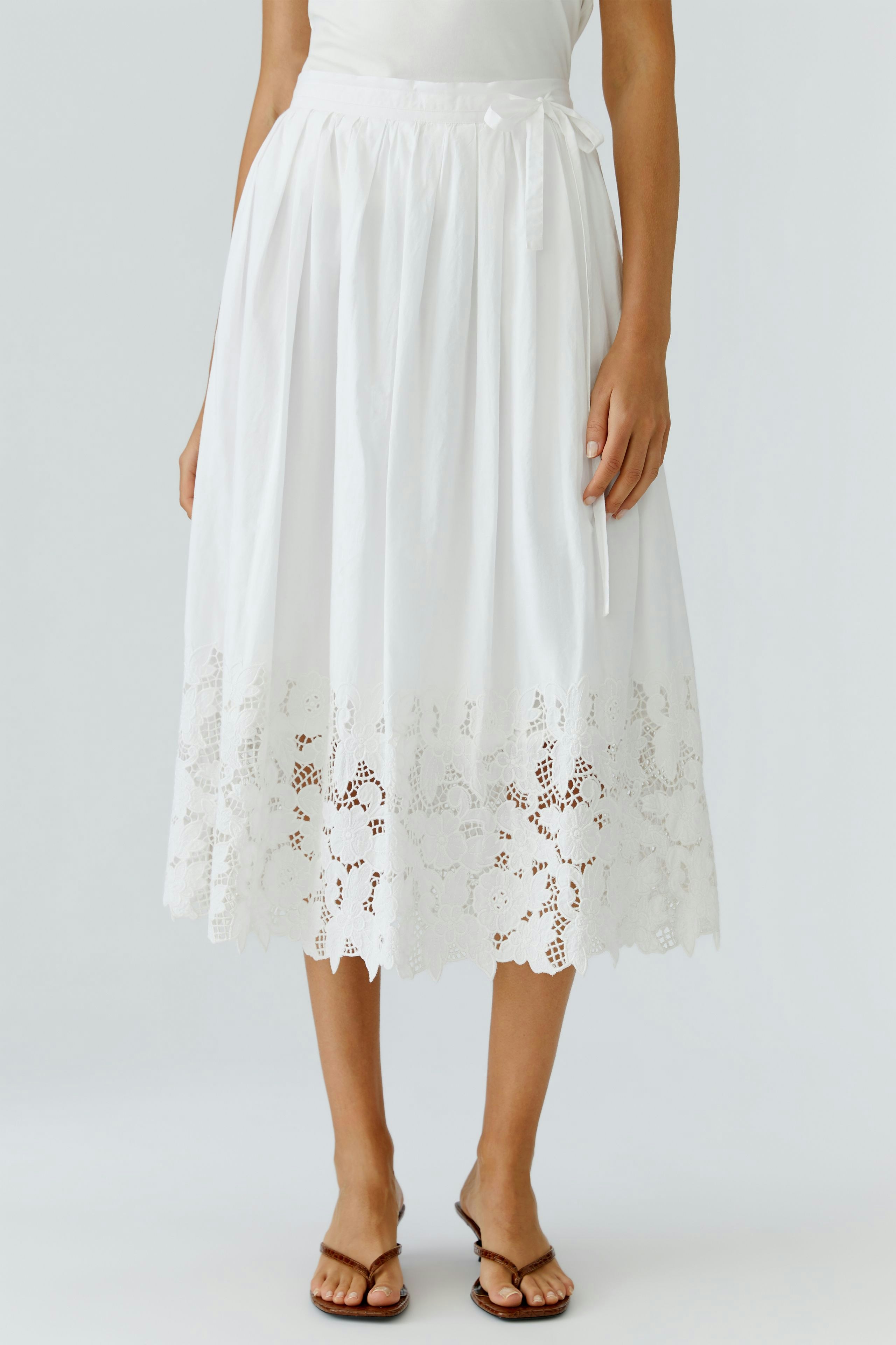 White pleated skirt: Woman in a flowy white skirt with lace trim, perfect for casual summer outings.