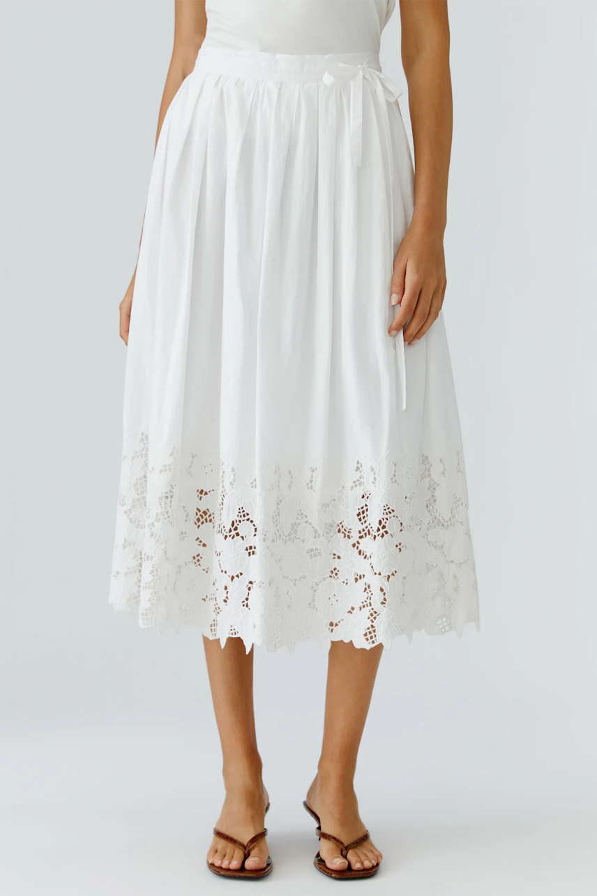 White pleated skirt: Woman in a flowy white skirt with lace trim, perfect for casual summer outings.