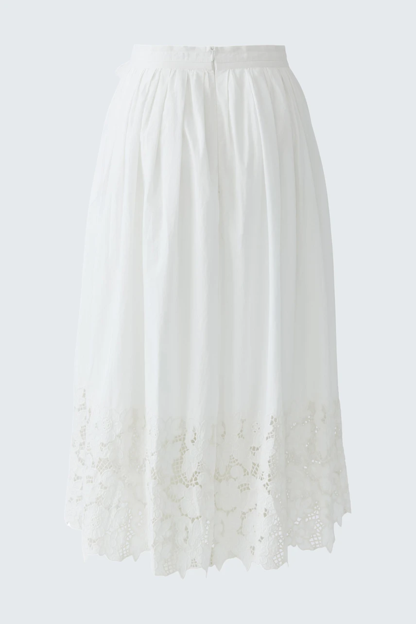 Lightweight white pleated skirt with lace detailing, worn by a woman.