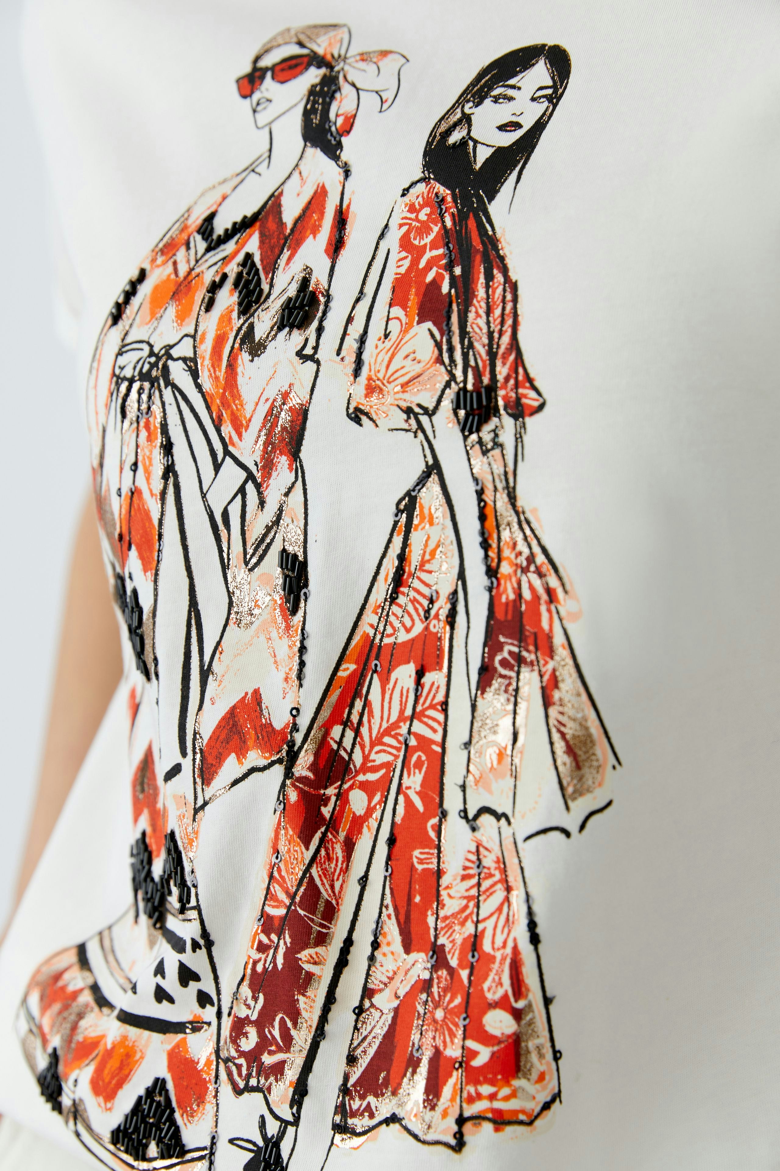 Damen-T-Shirt: Frau trägt ein weißes T-Shirt mit buntem, künstlerischem Druck von zwei stilisierten Figuren.