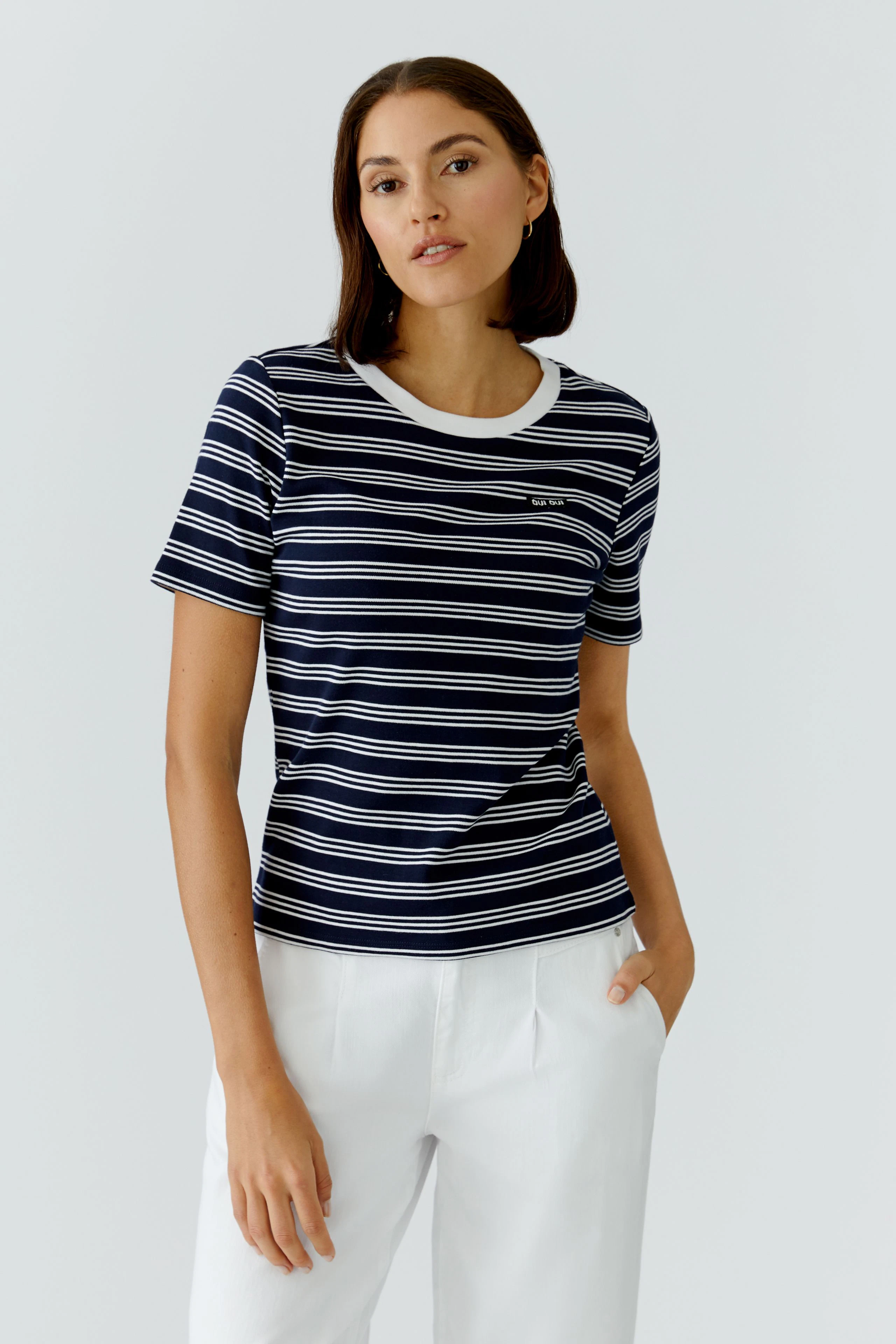 Casual women's T-shirt: Young woman in a navy striped tee with a white collar, paired with light trousers.