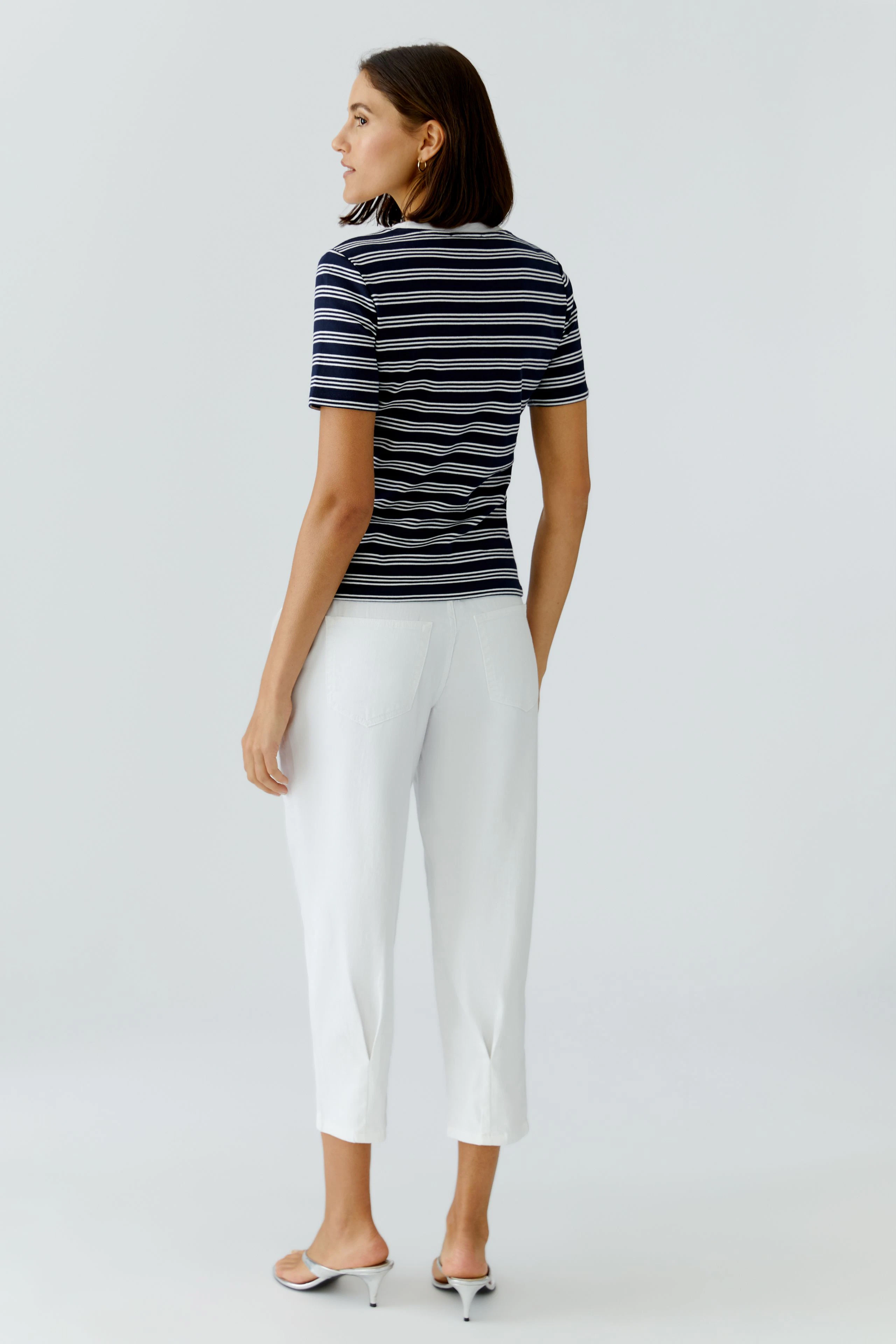 Casual women's T-shirt: Young woman in a striped tee and white pants, showcasing a relaxed style.