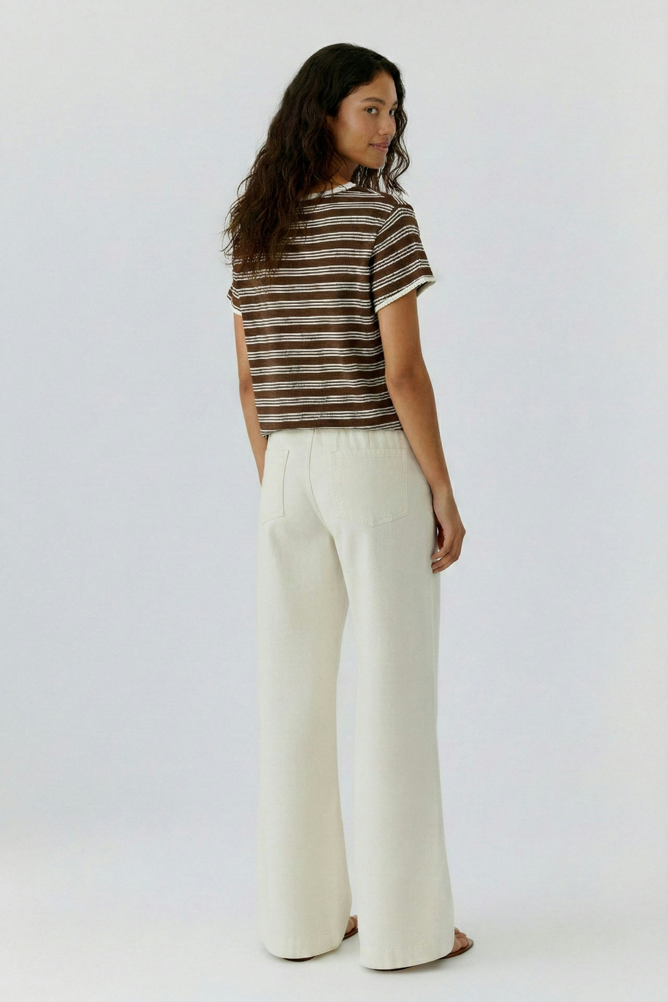 Bequemes Damen-T-Shirt: Frau mit gestreiftem Shirt und lässigen Hosen steht entspannt.