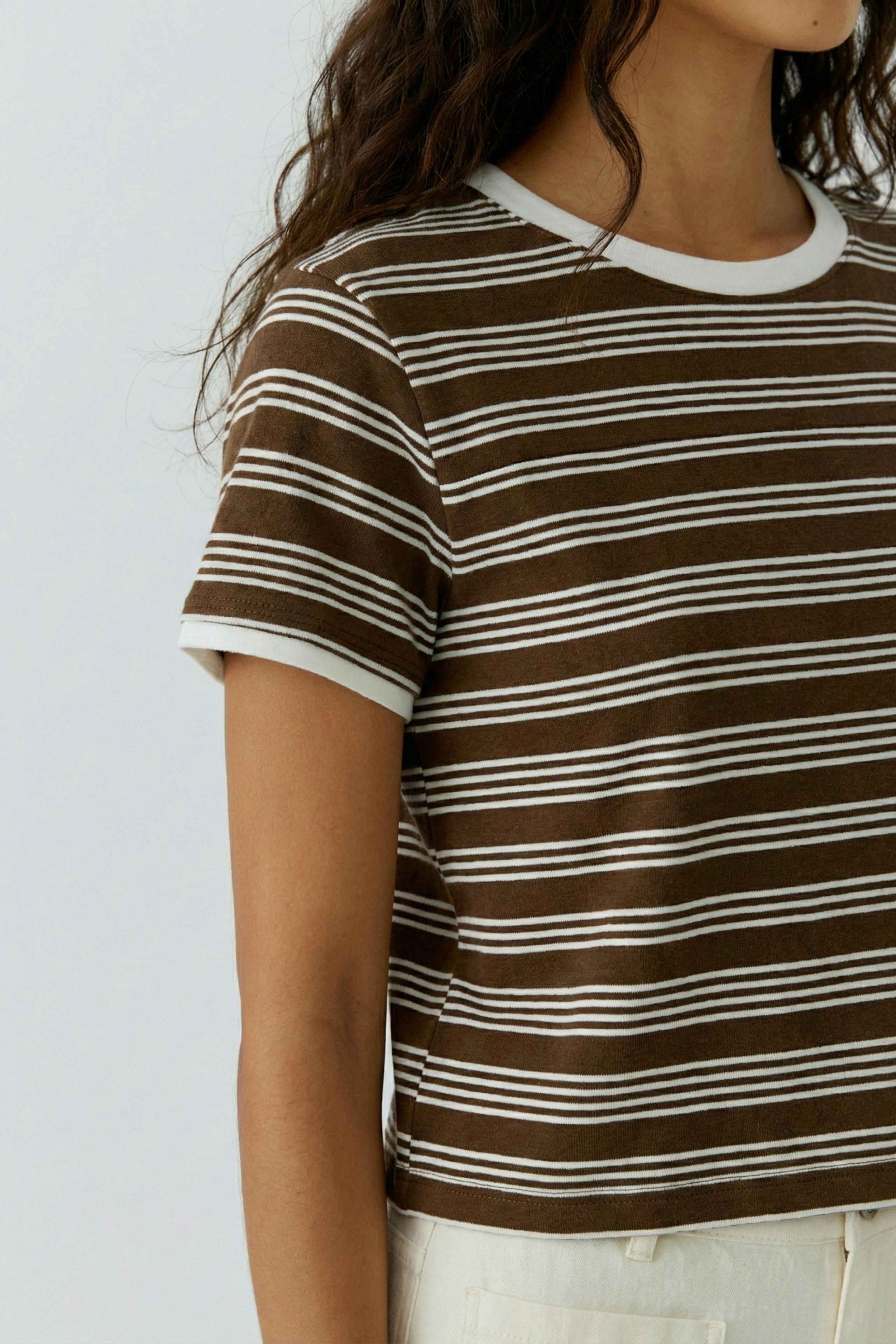 Damen-T-Shirt: Junge Frau trägt ein gestreiftes, braunes T-Shirt mit weißen Akzenten.