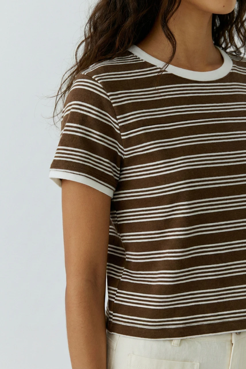 Damen-T-Shirt: Junge Frau trägt ein gestreiftes, braunes T-Shirt mit weißen Akzenten.