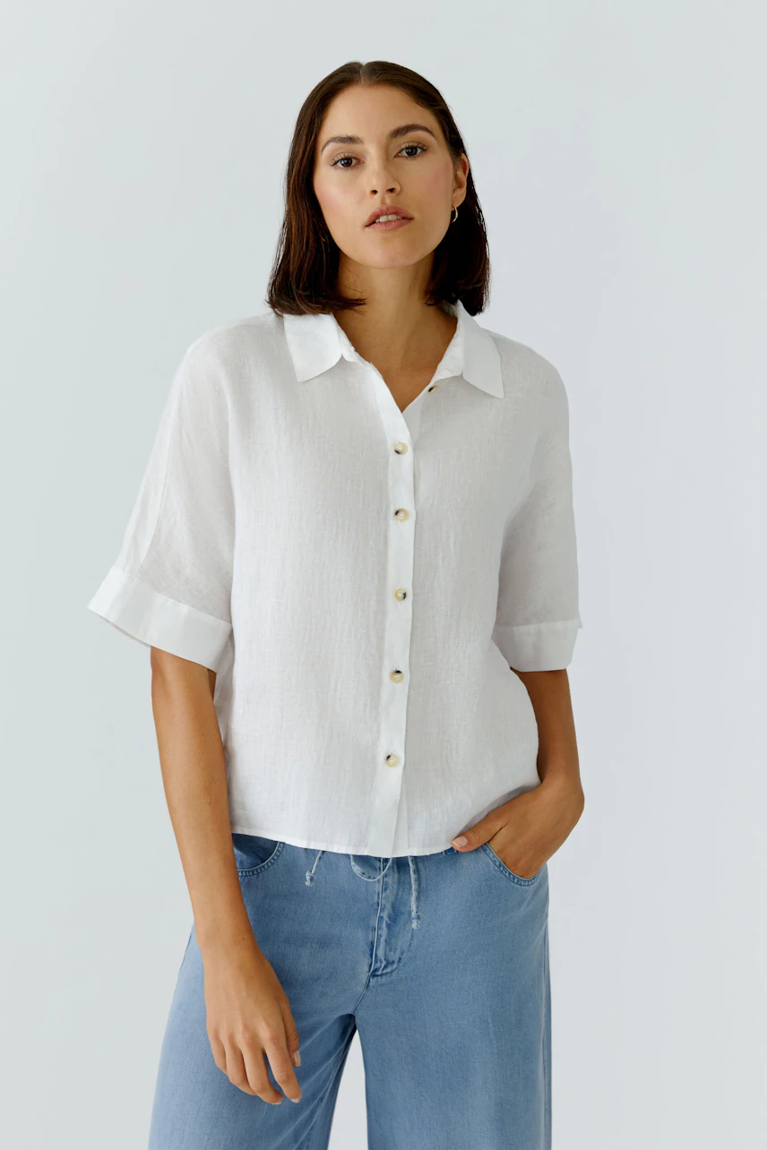 Casual women's blouse: Woman in a white short-sleeve blouse with buttons, paired with relaxed jeans.