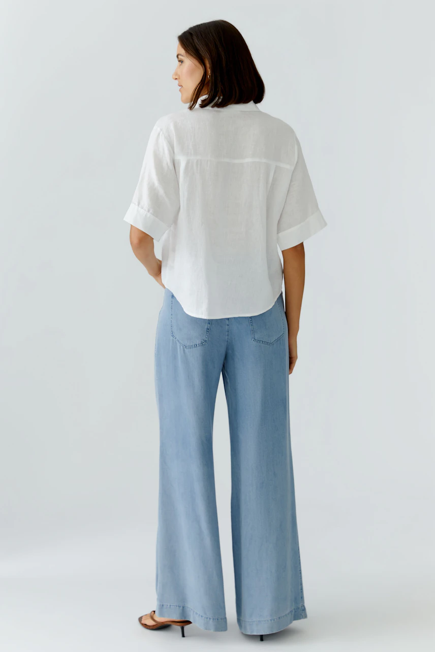 Casual women's blouse: A woman in a loose-fitting white blouse and wide-leg jeans, showcasing a relaxed style.