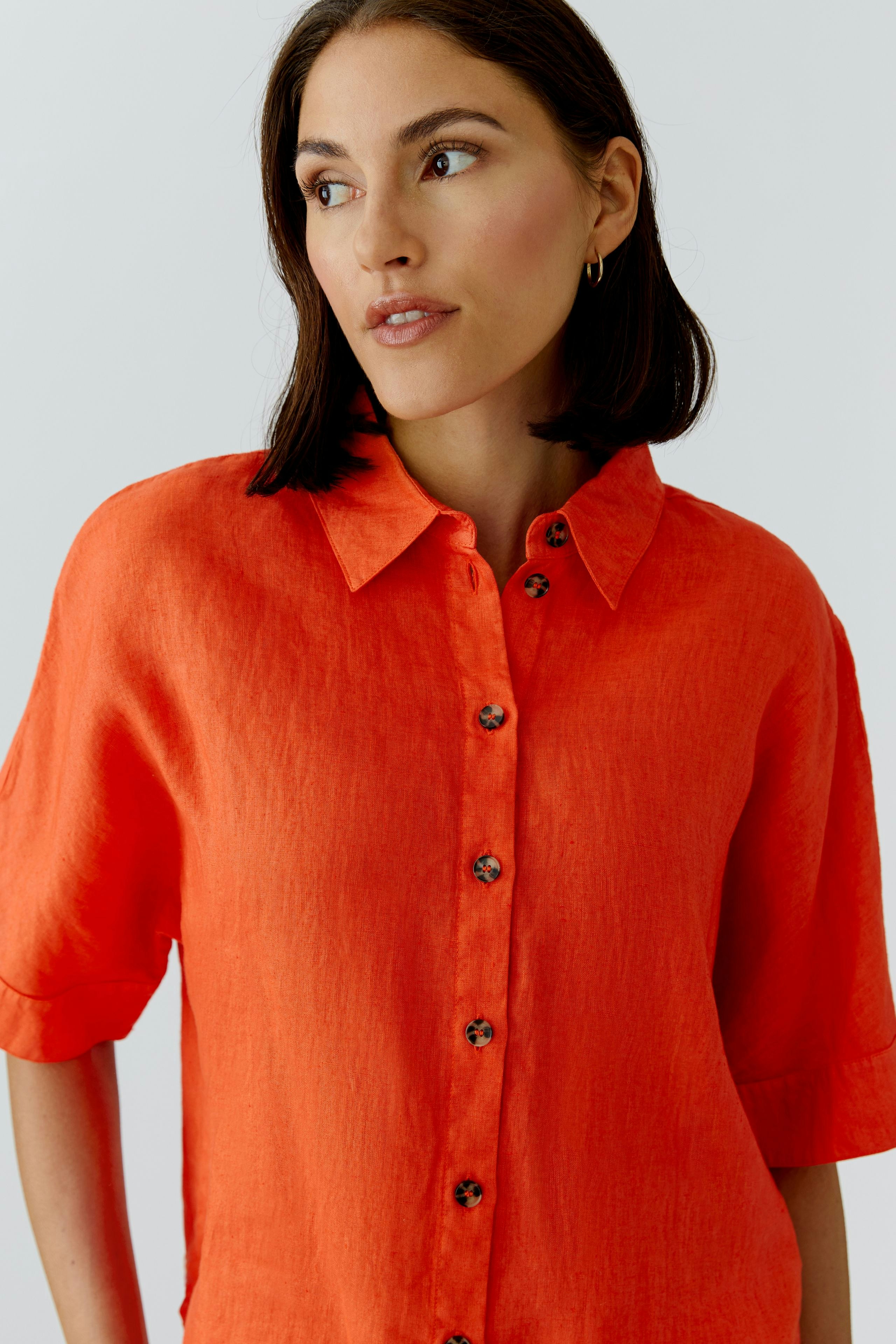 Casual women's blouse: A woman in a bright orange button-up blouse with short sleeves.