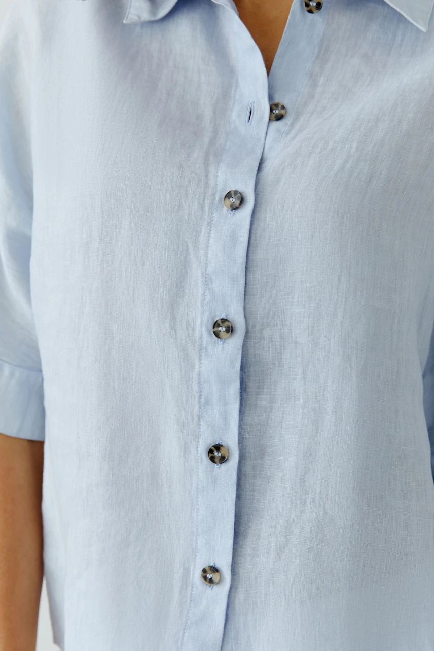 Light blue blouse: Woman in a relaxed fit, short-sleeve blouse with button details.