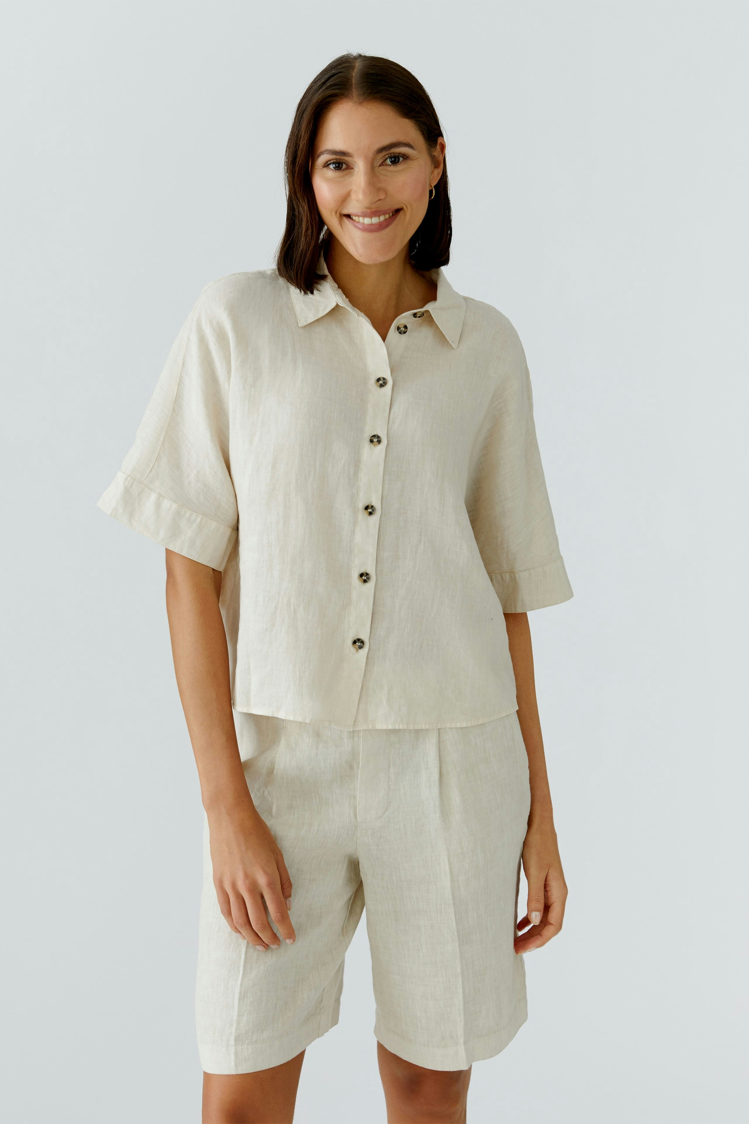 Casual women's blouse: A woman in a light beige short-sleeve blouse with buttons, smiling confidently.