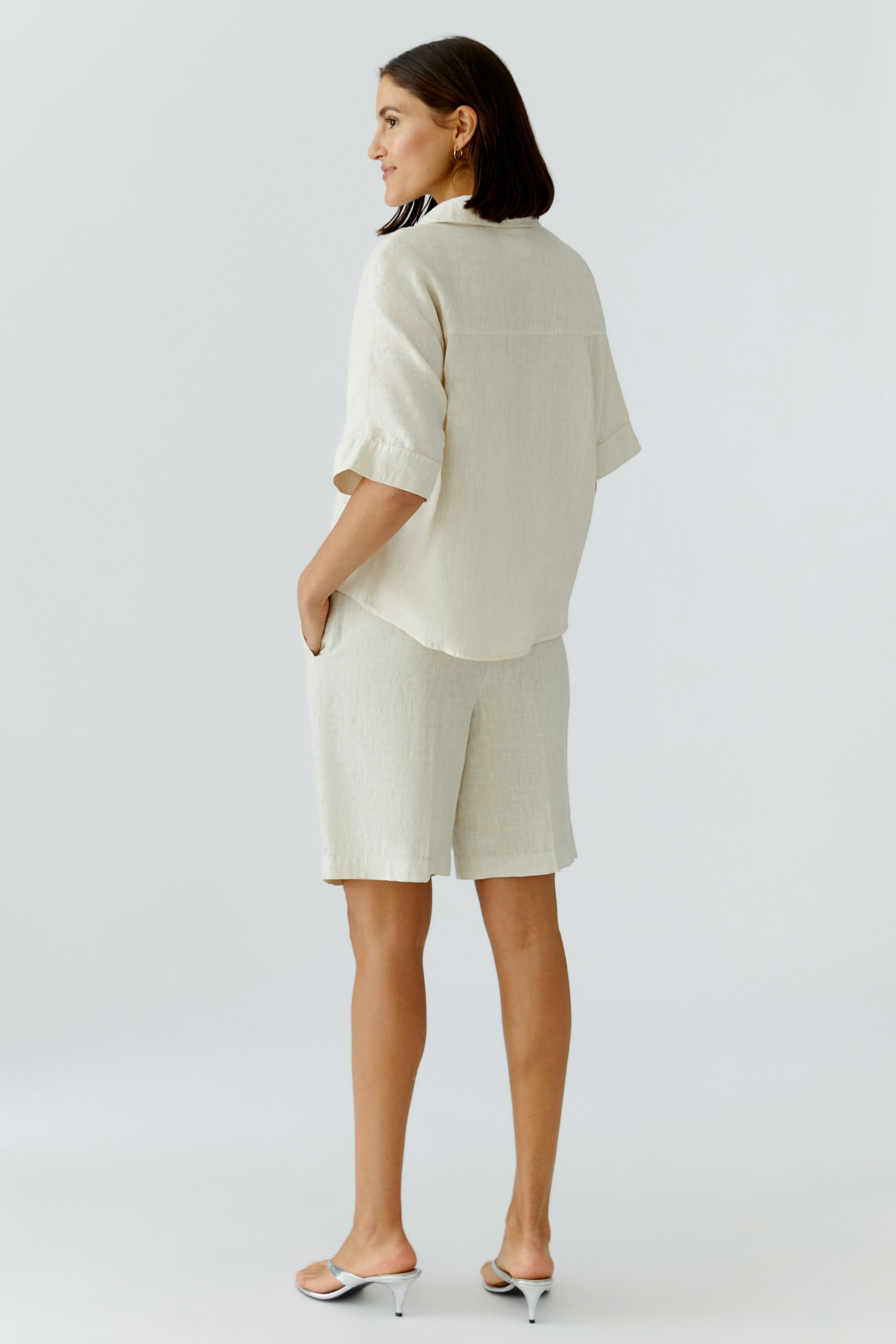 Casual women's blouse: A woman in a light beige short-sleeve blouse with a relaxed fit.
