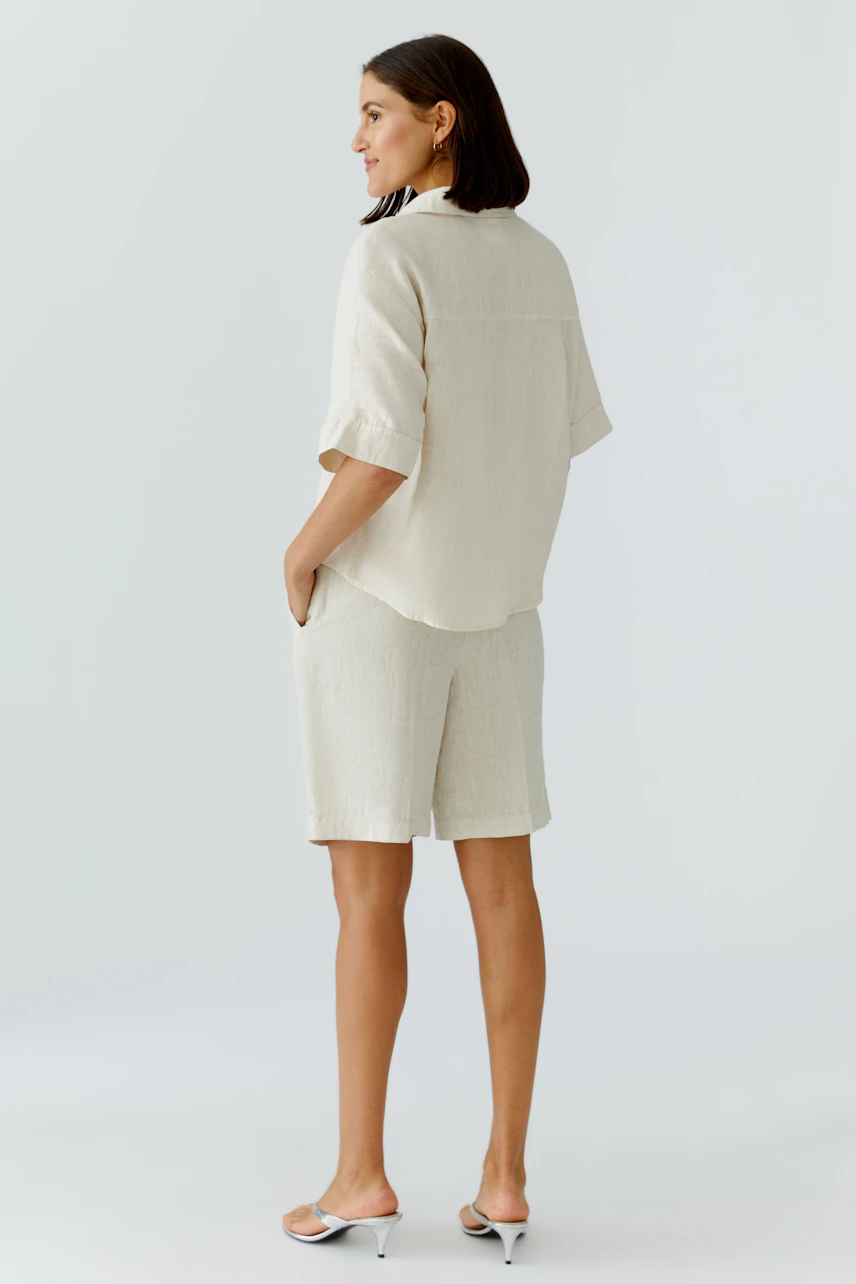 Casual women's blouse: A woman in a light beige short-sleeve blouse with a relaxed fit.