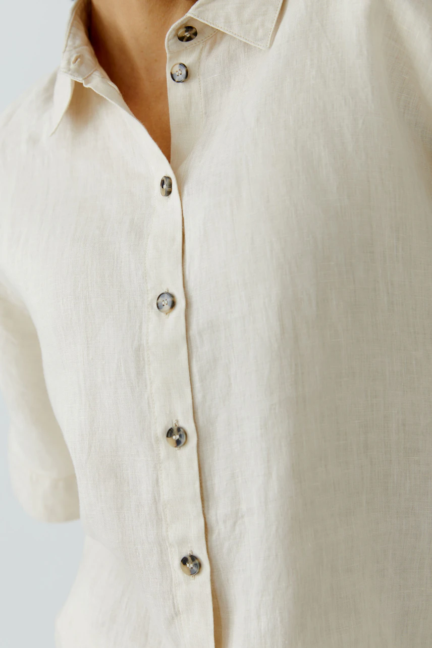 Light beige blouse: Woman in a relaxed fit, short-sleeve blouse with button details.
