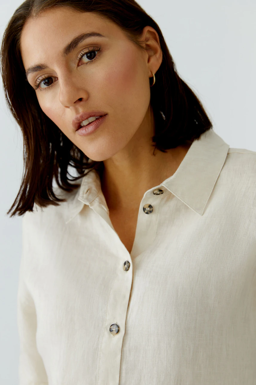 Casual women's blouse: A woman in a light-colored blouse with buttons, showcasing a relaxed style.