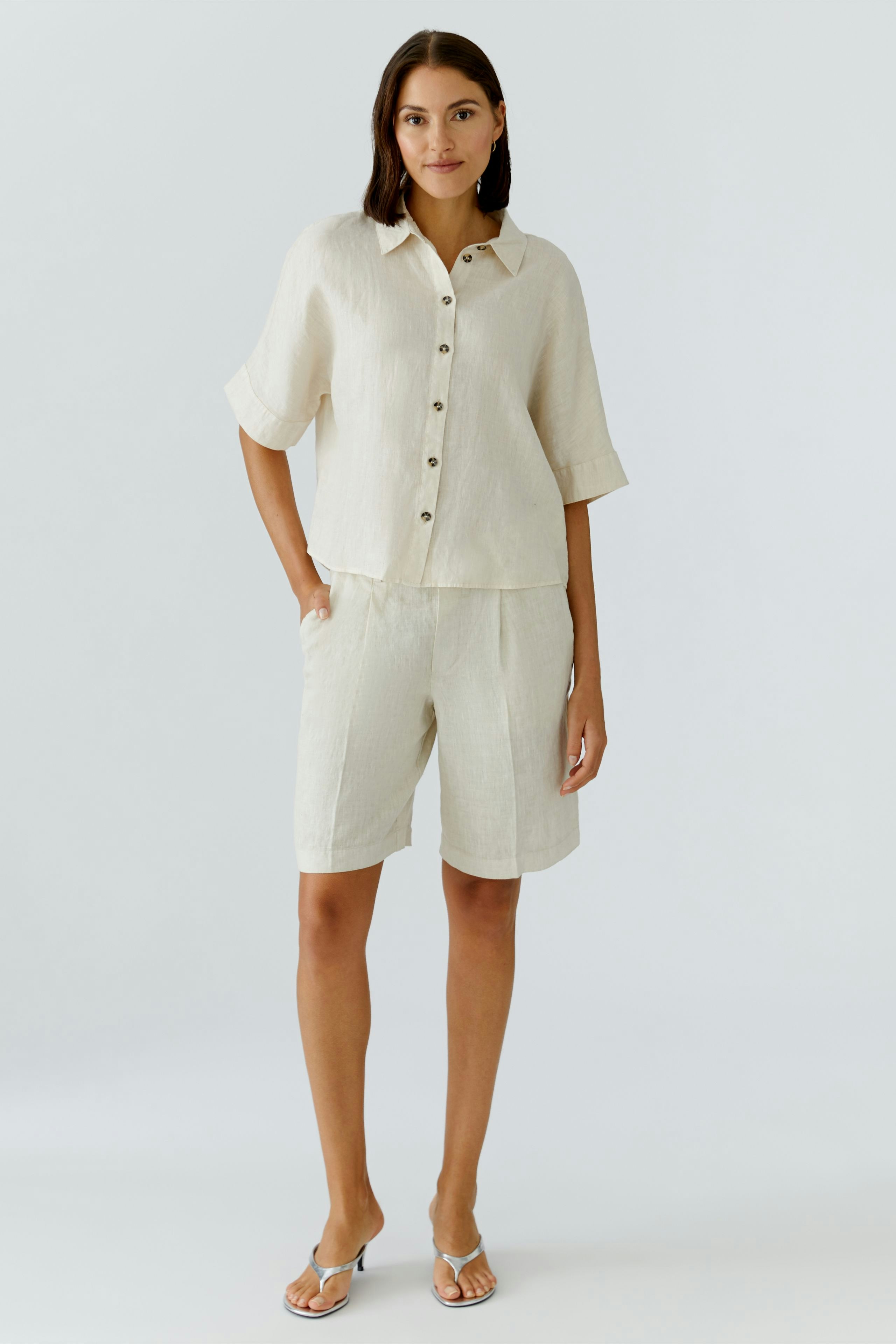 Casual women's blouse: A woman in a light linen blouse with buttons and relaxed fit shorts.