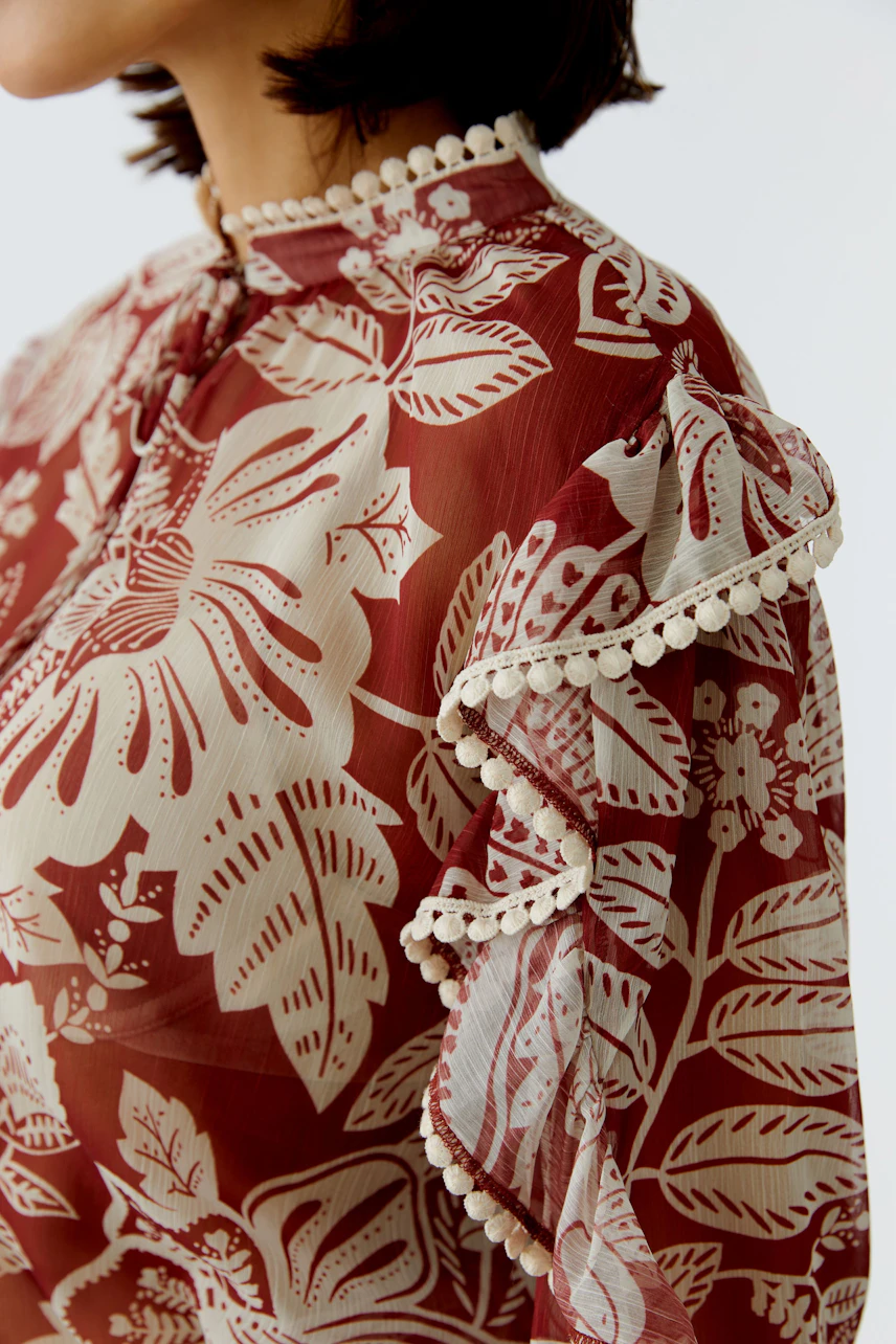 Damen-Bluse mit floralem Muster und Rüschen, die eine frische, lässige Ausstrahlung vermittelt.