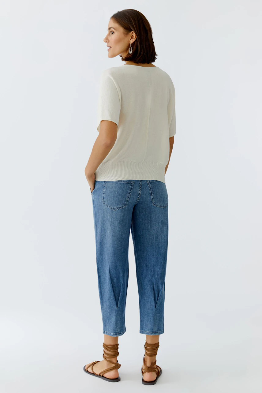 Casual women's pullover: A woman in a light pullover paired with relaxed denim pants, showcasing a laid-back style.